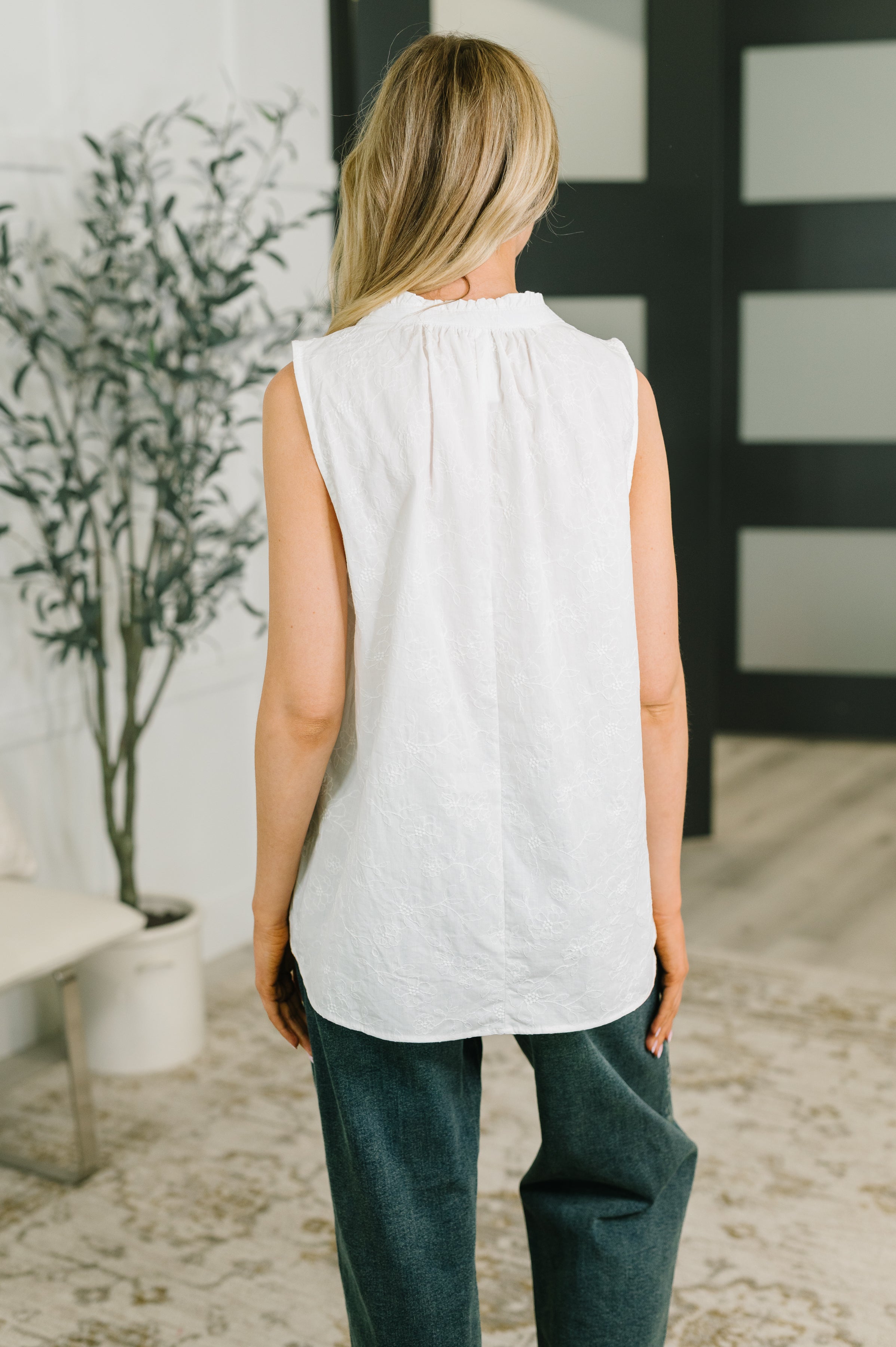 Back view of woman wearing sleeveless off white embroidered tank with gathered neckline and relaxed fit indoors