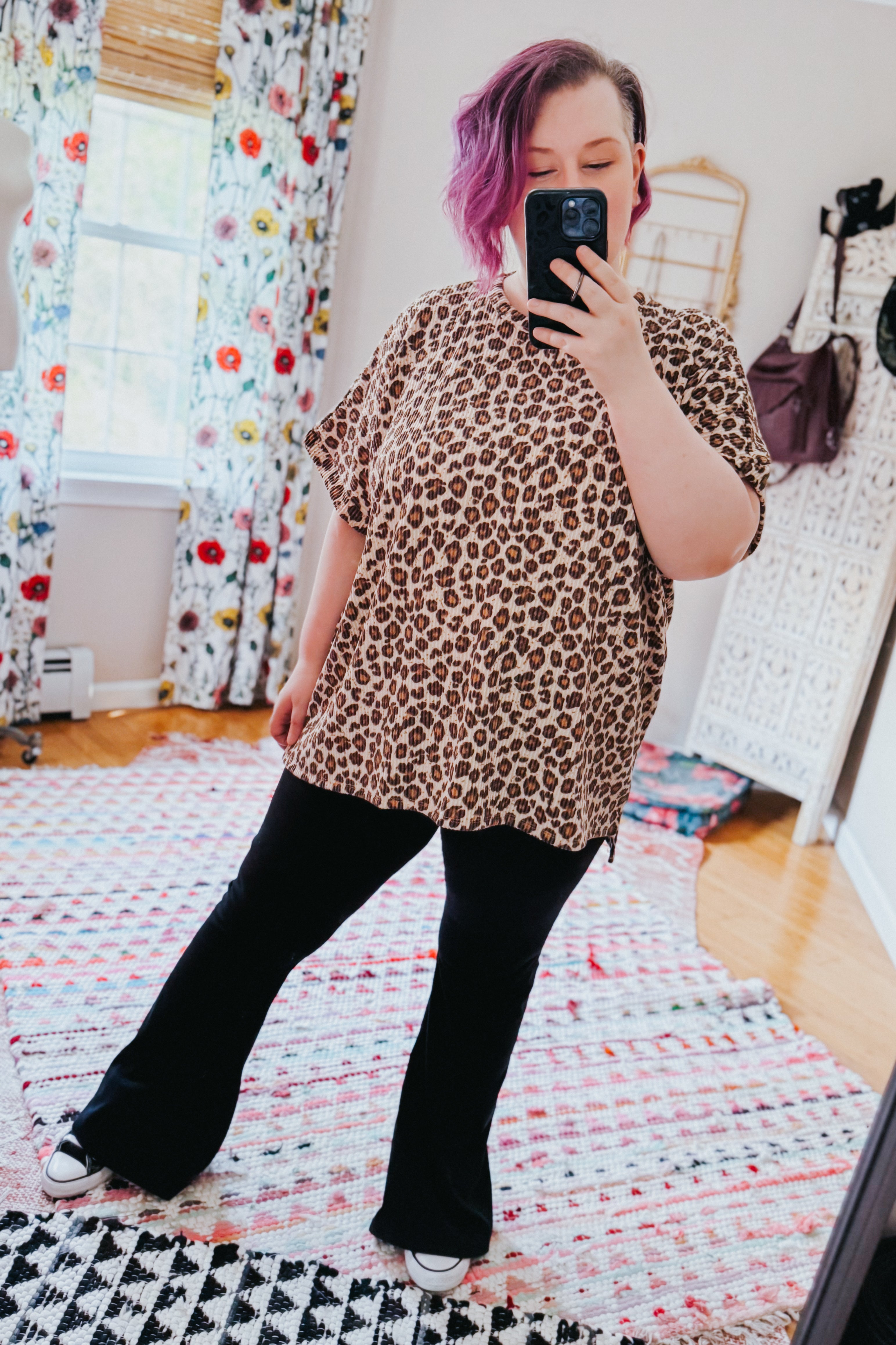 Woman with purple hair taking mirror selfie wearing loose leopard print Canyon Wild Top with black pants and sneakers