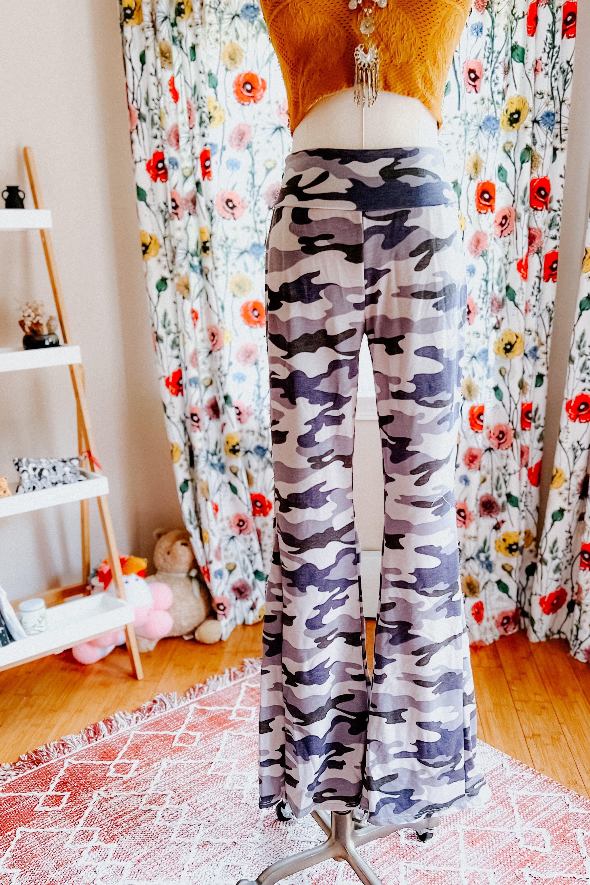 High-waisted flare pants with grey and navy blue camouflage pattern displayed on mannequin in cozy room