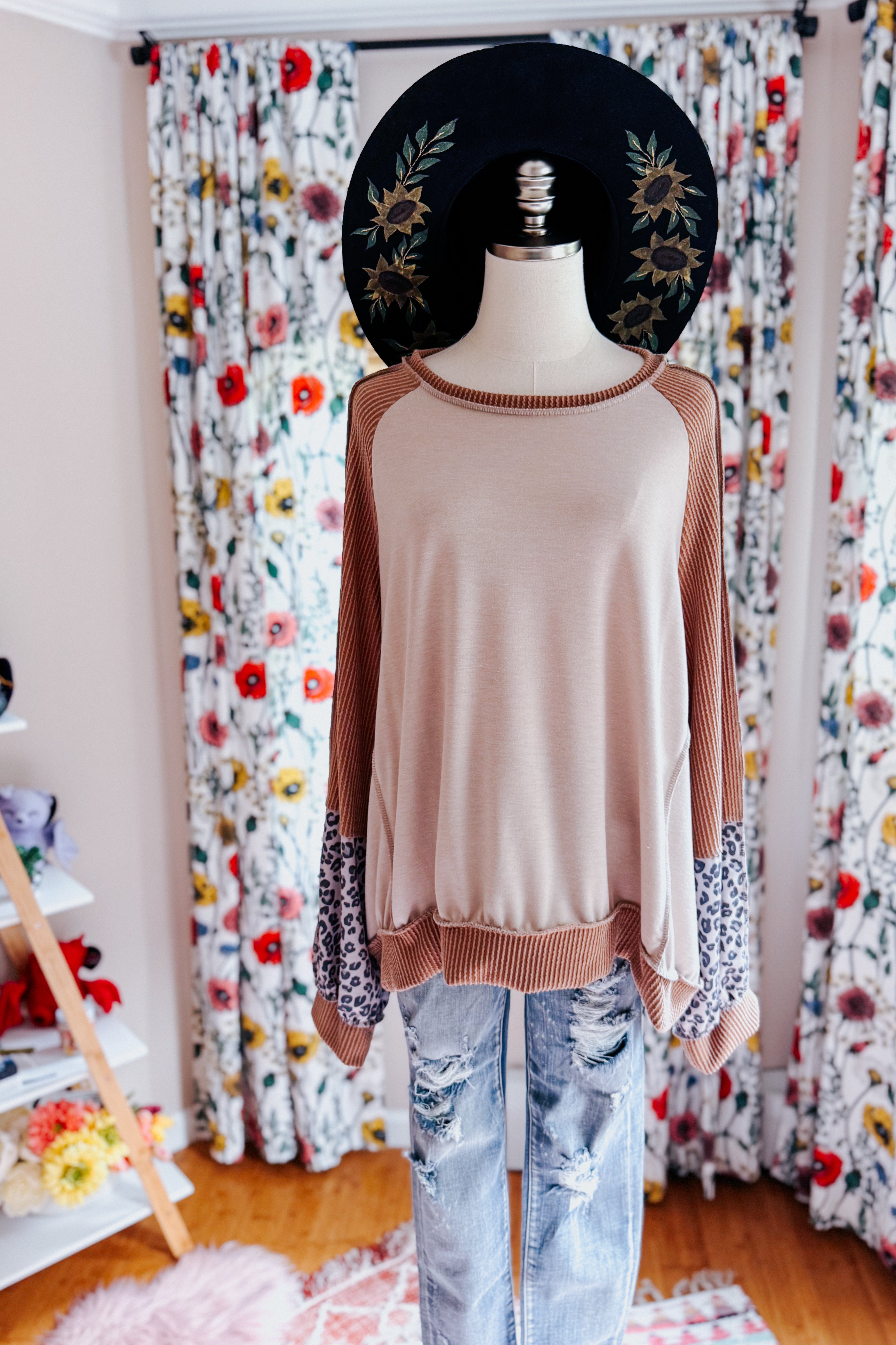 Loose fit dolman sleeve colorblock top with beige center, rust ribbed sleeves, and leopard print cuffs on mannequin indoors