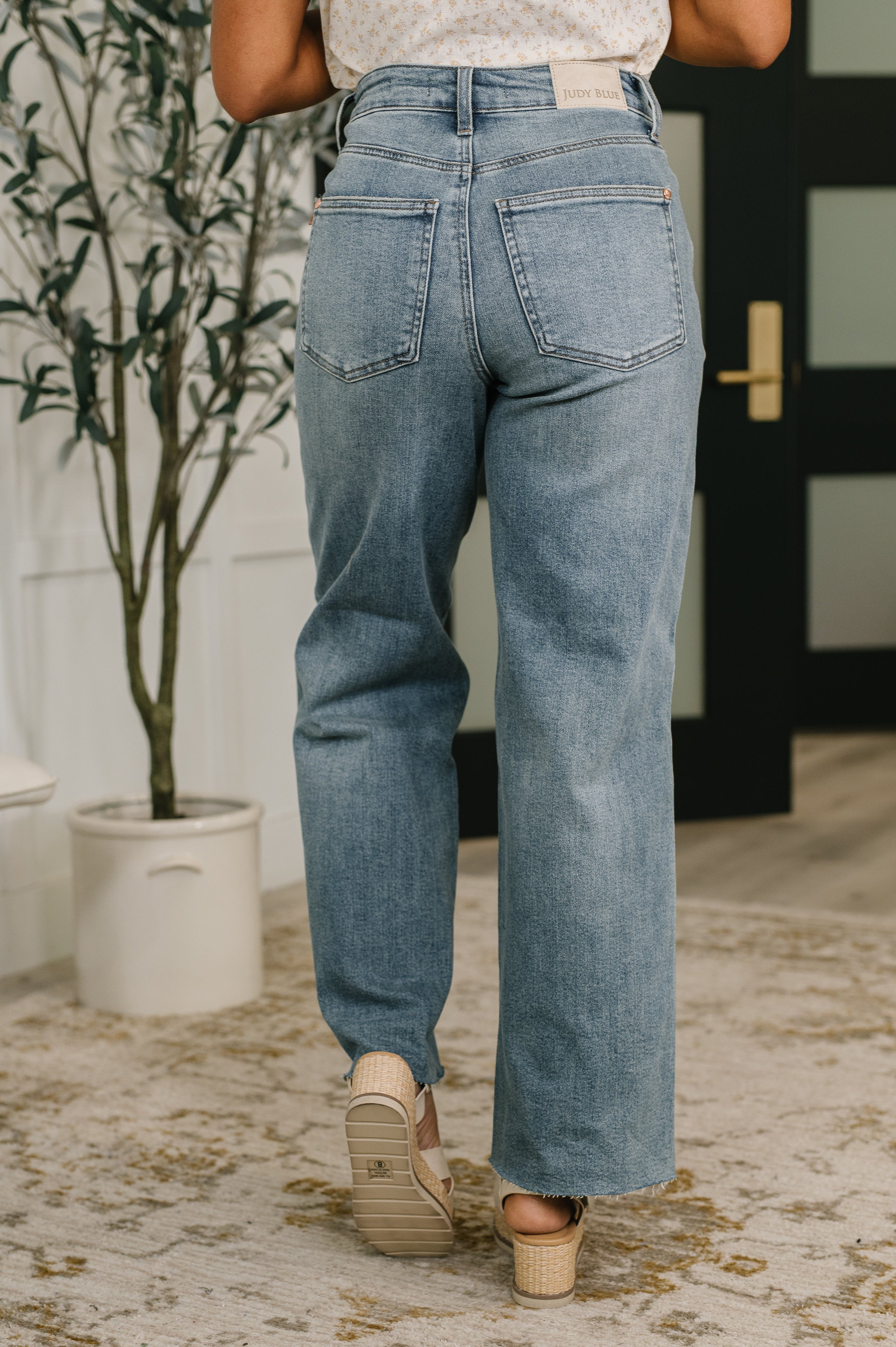 Back view of blue high waist baggy jeans paired with beige open-toe heels in cozy indoor setting