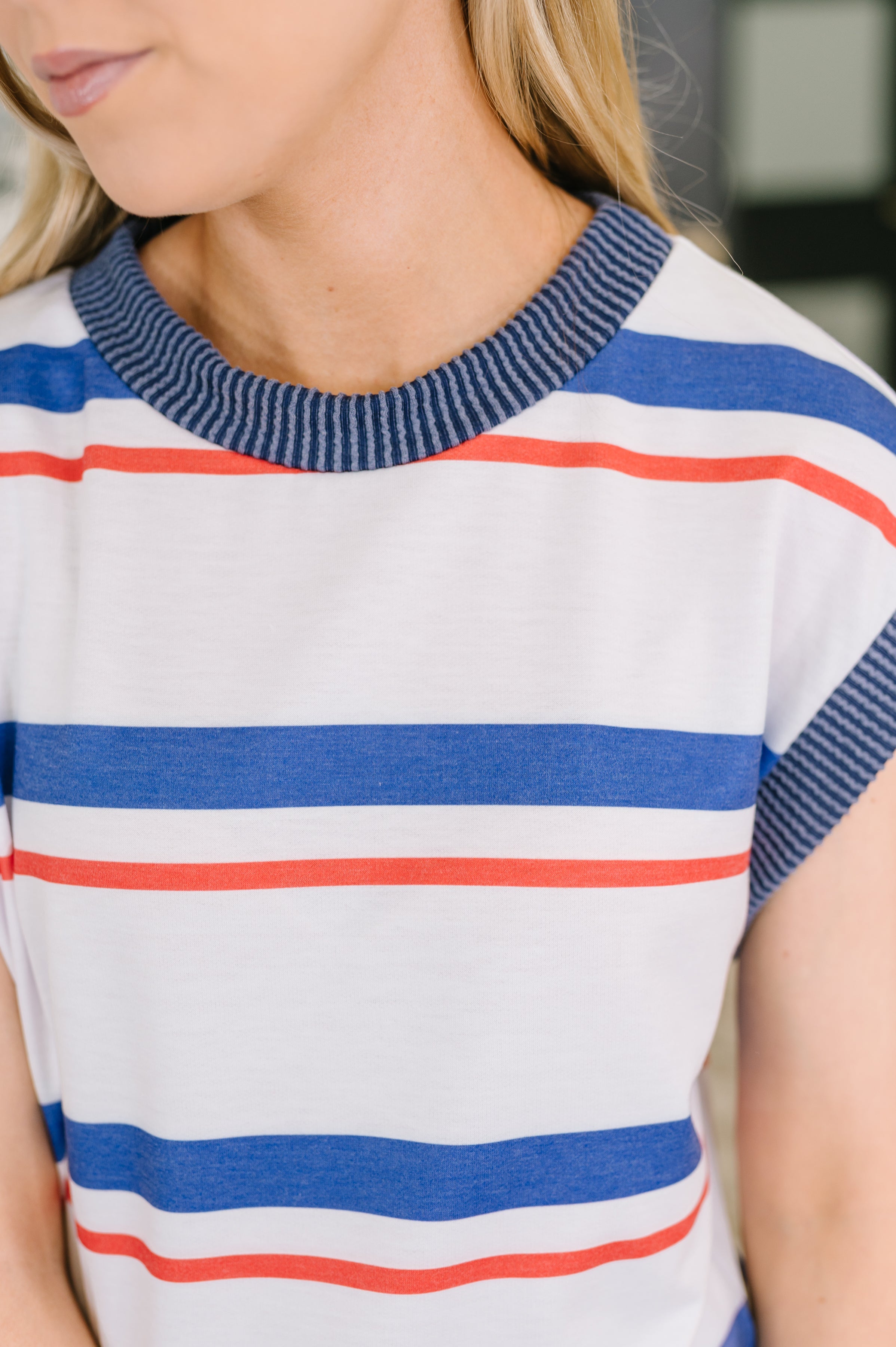 Close-up of sleeveless top with bold blue and red stripes and ribbed navy collar, showcasing soft French terry fabric.