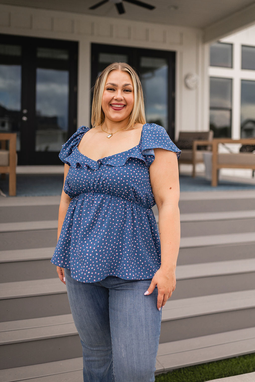 Plus size woman with blonde hair wearing blue polka dot Connect the Dots peplum blouse with ruffle sleeves outdoors