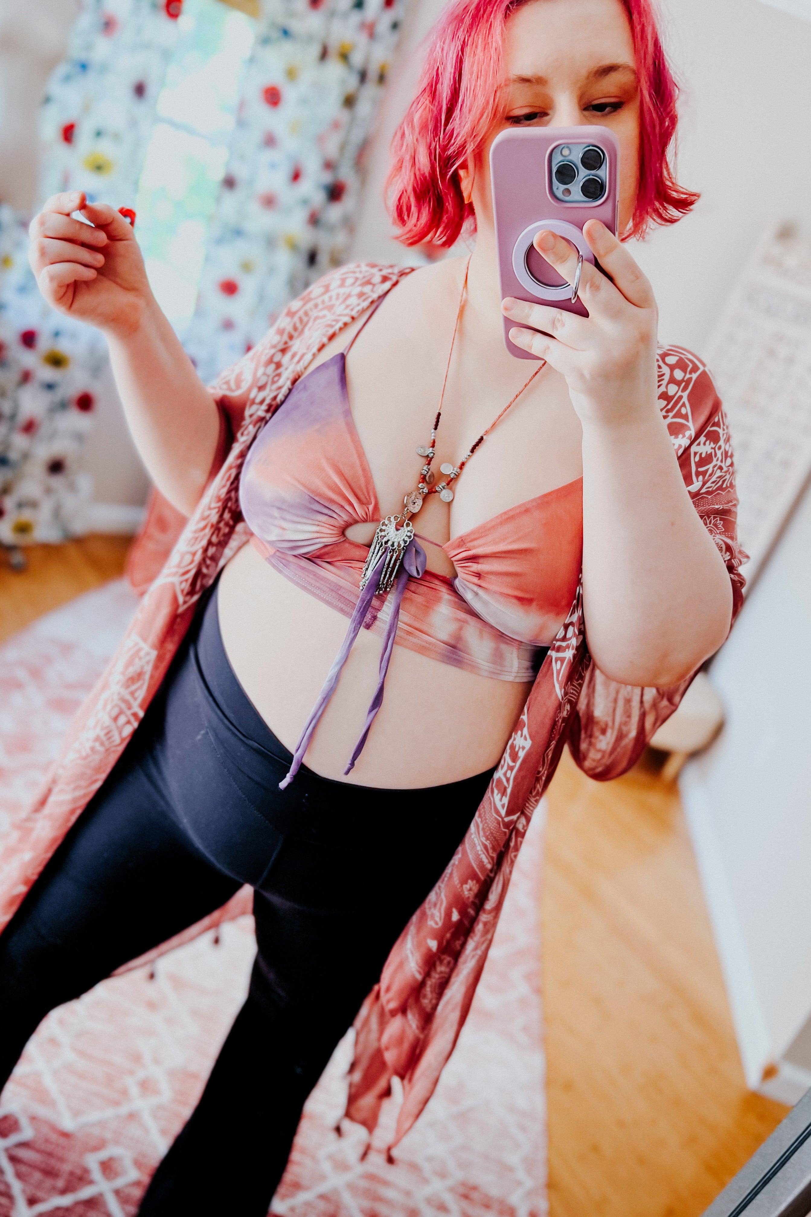 Plus size woman wearing multicolor tie dye mesh brami top and patterned kimono taking mirror selfie indoors