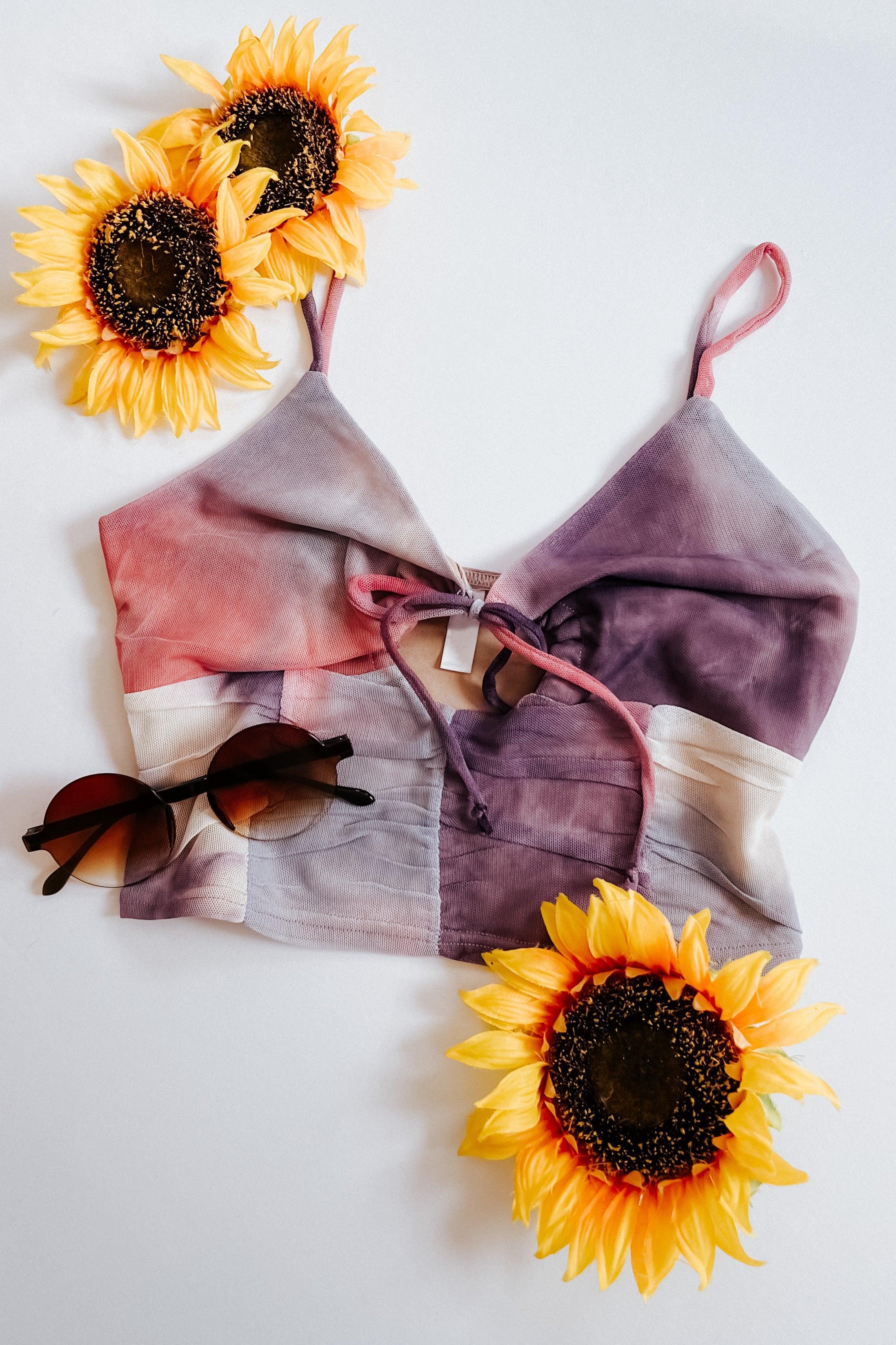 Crystal Visions tie dye mesh brami top with sunglasses and three sunflowers on white background