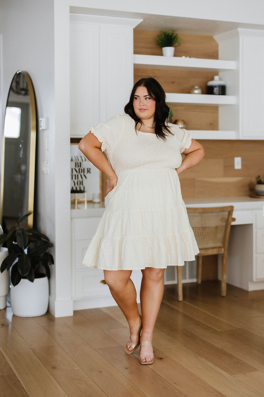 Woman wearing ivory square neck dress with puff sleeves and tiered skirt in bright modern room