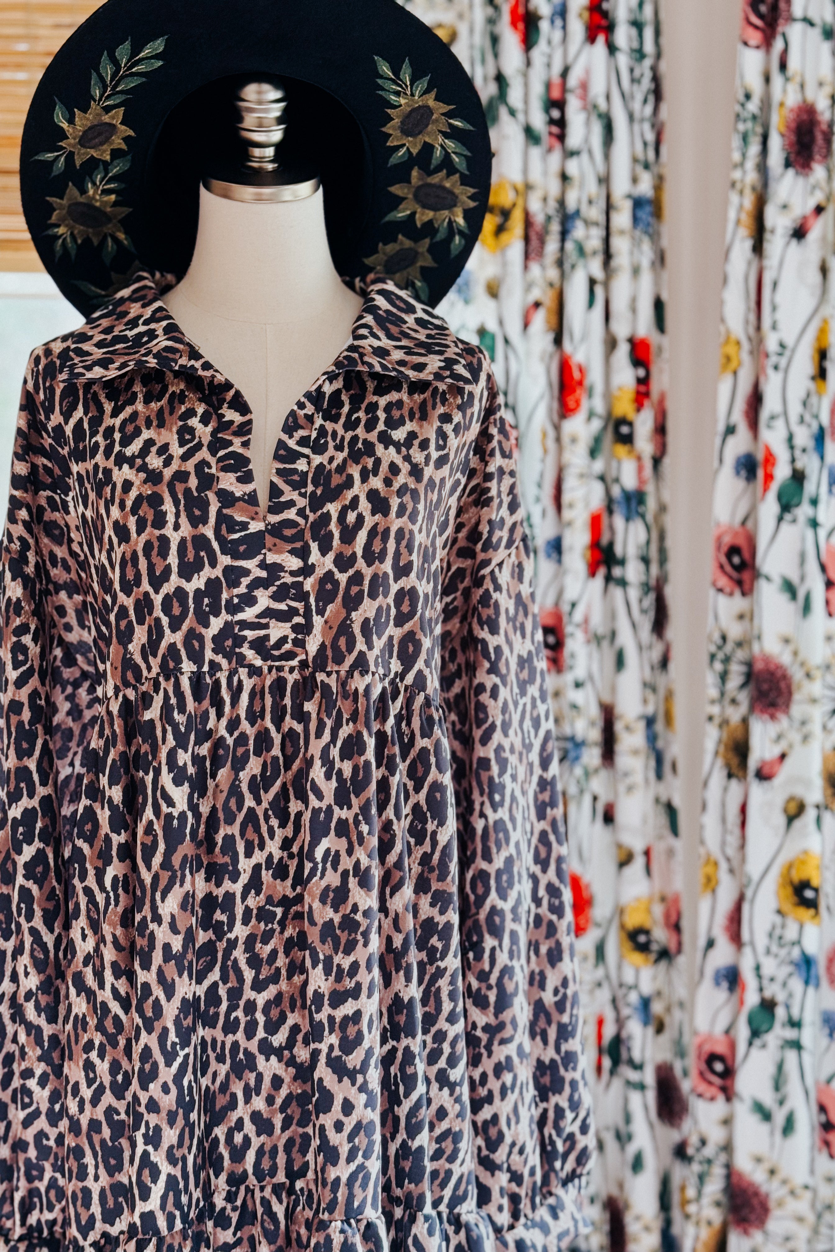 Leopard print babydoll dress with collar on dress form wearing black hat embroidered with sunflowers