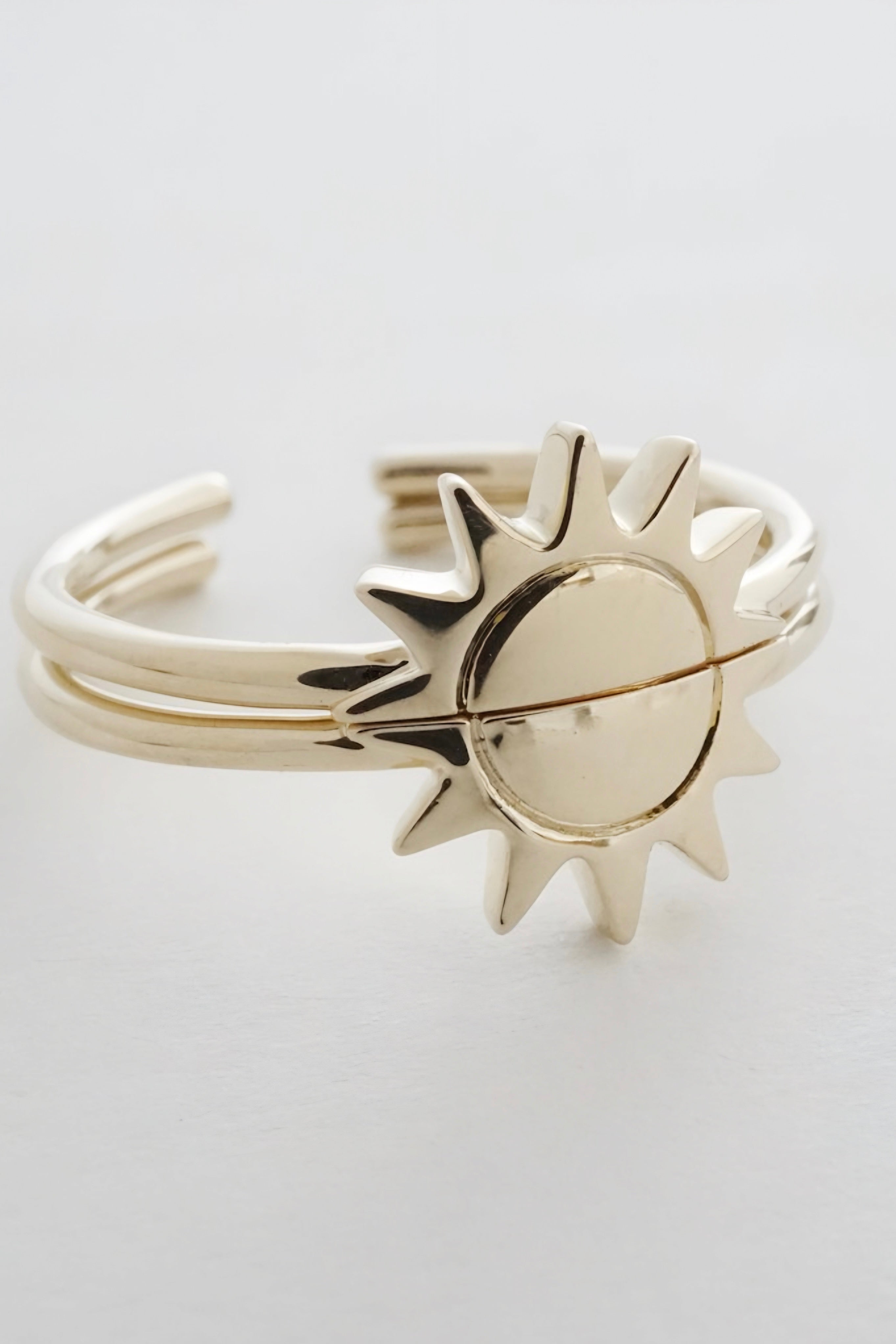 Gold open-ended ring duo with sun motif on white background highlighting polished metal details