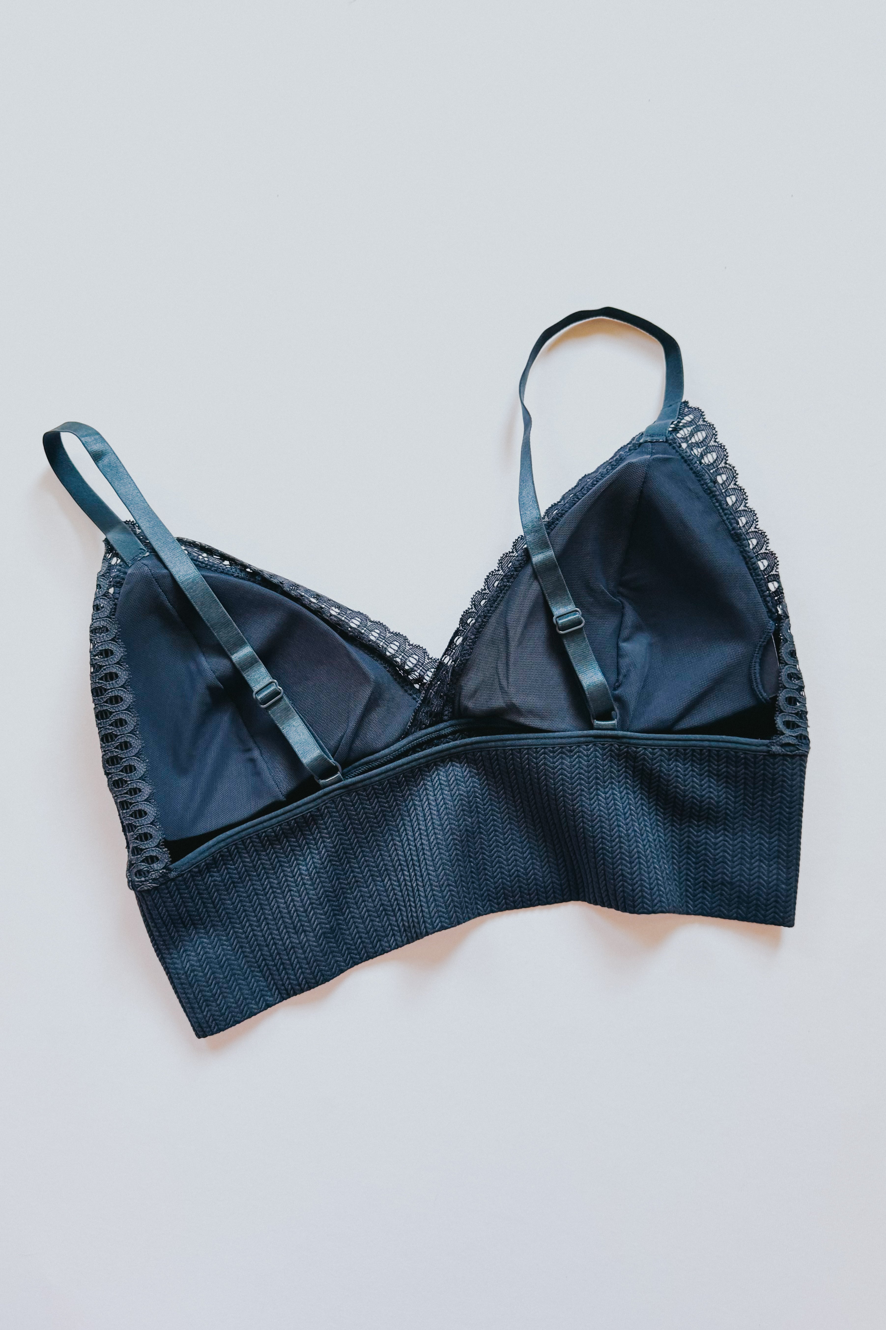 Dusty blue Daydream lace bralette with adjustable straps and textured band laid flat on pale gray background