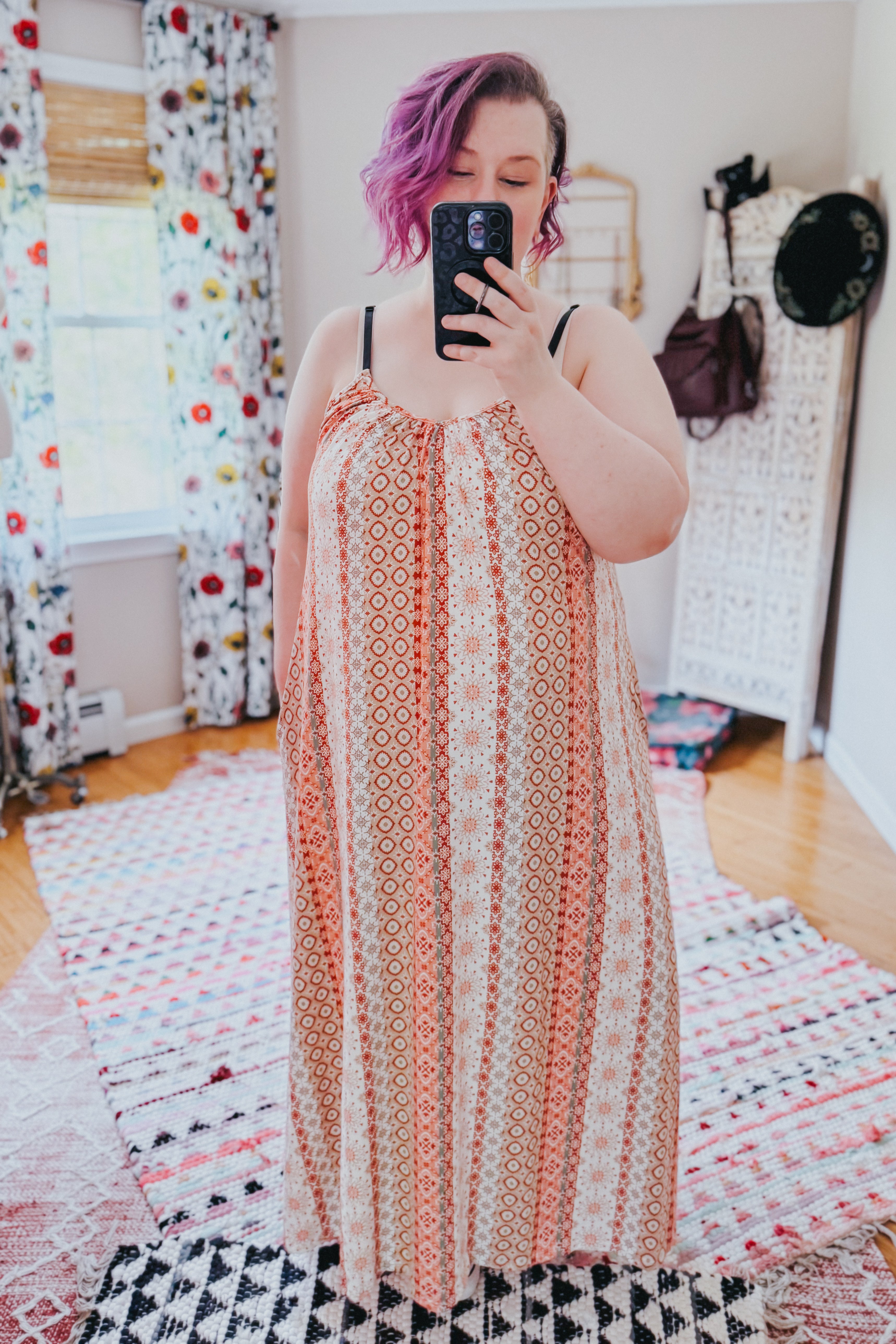 Woman with short purple hair wearing sleeveless patterned maxi dress taking selfie indoors</125