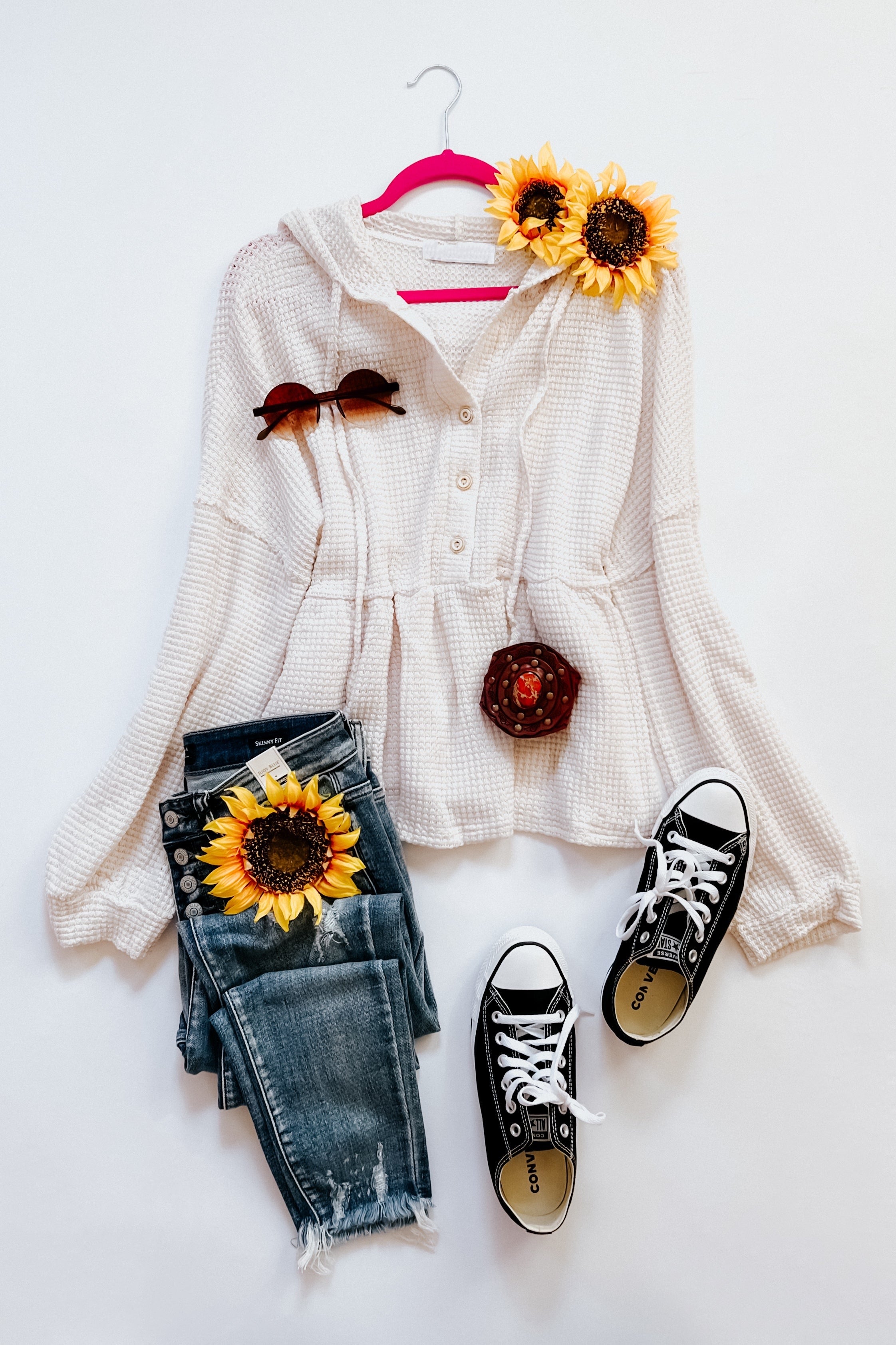 Off-white waffle knit hoodie with button front and gathered waist styled with distressed denim jeans and black sneakers