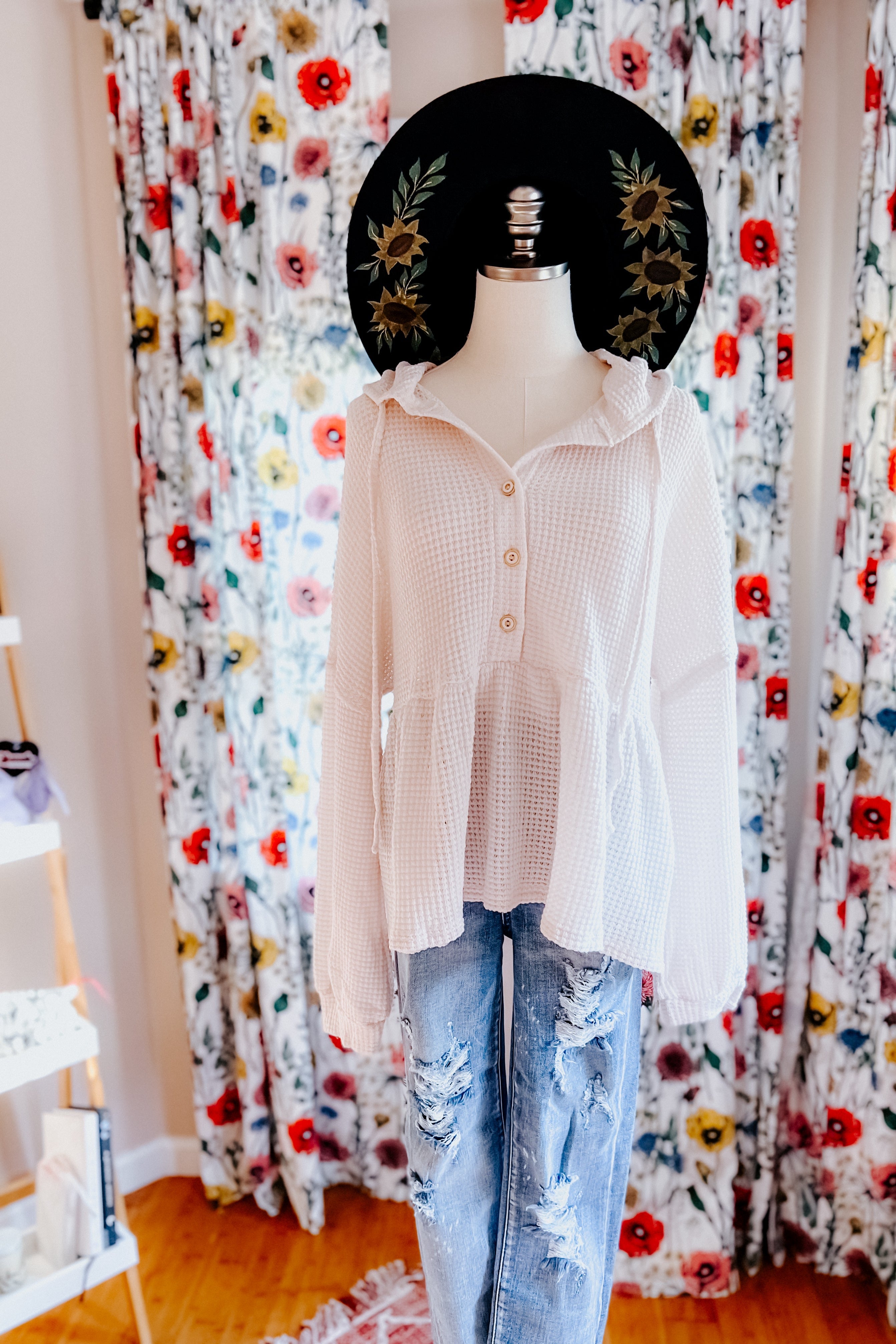 Off-white waffle knit hoodie with button front and peplum hem styled with distressed light wash jeans on mannequin