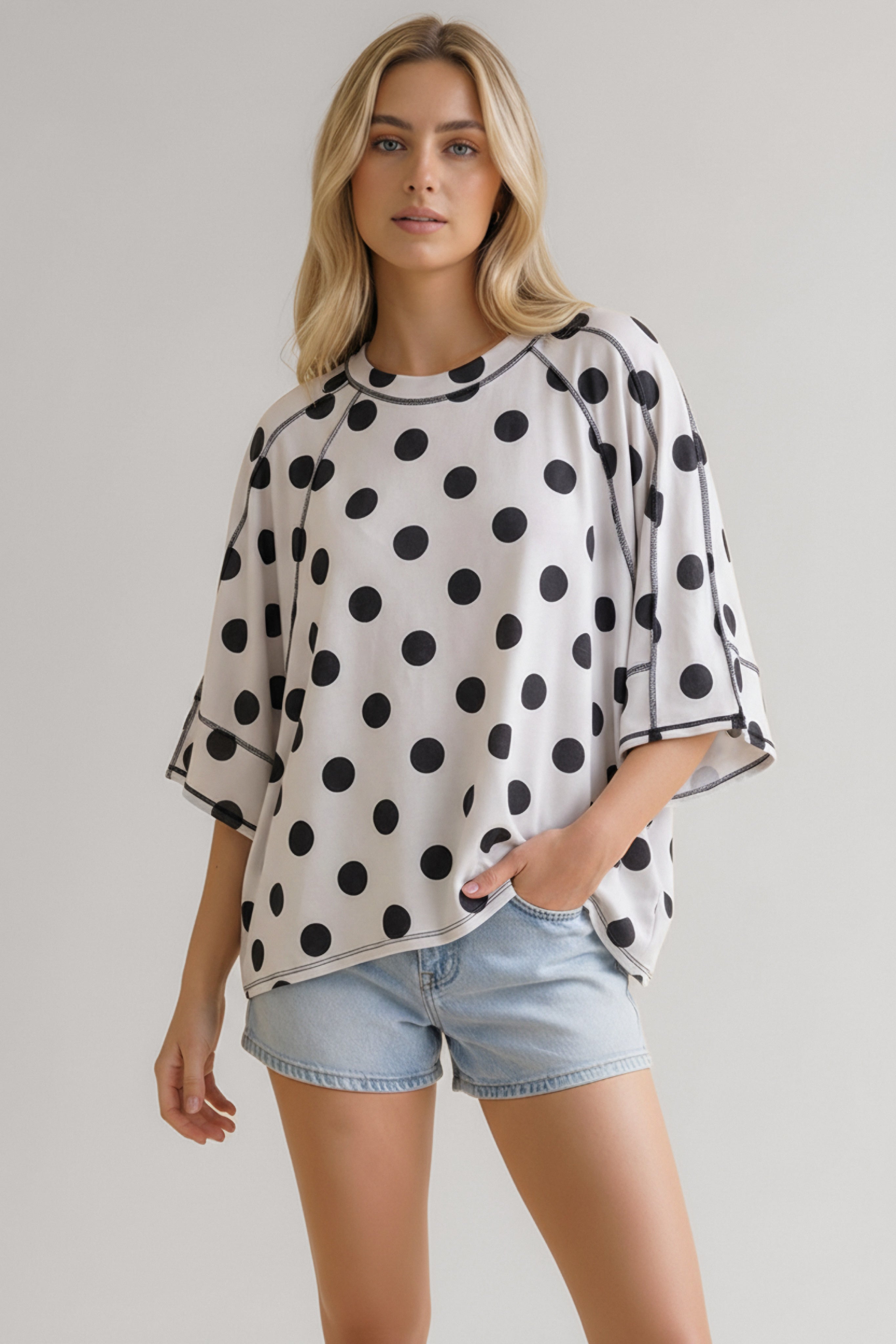 Woman wearing oversized black and white polka dot tee with contrast stitching paired with light denim shorts