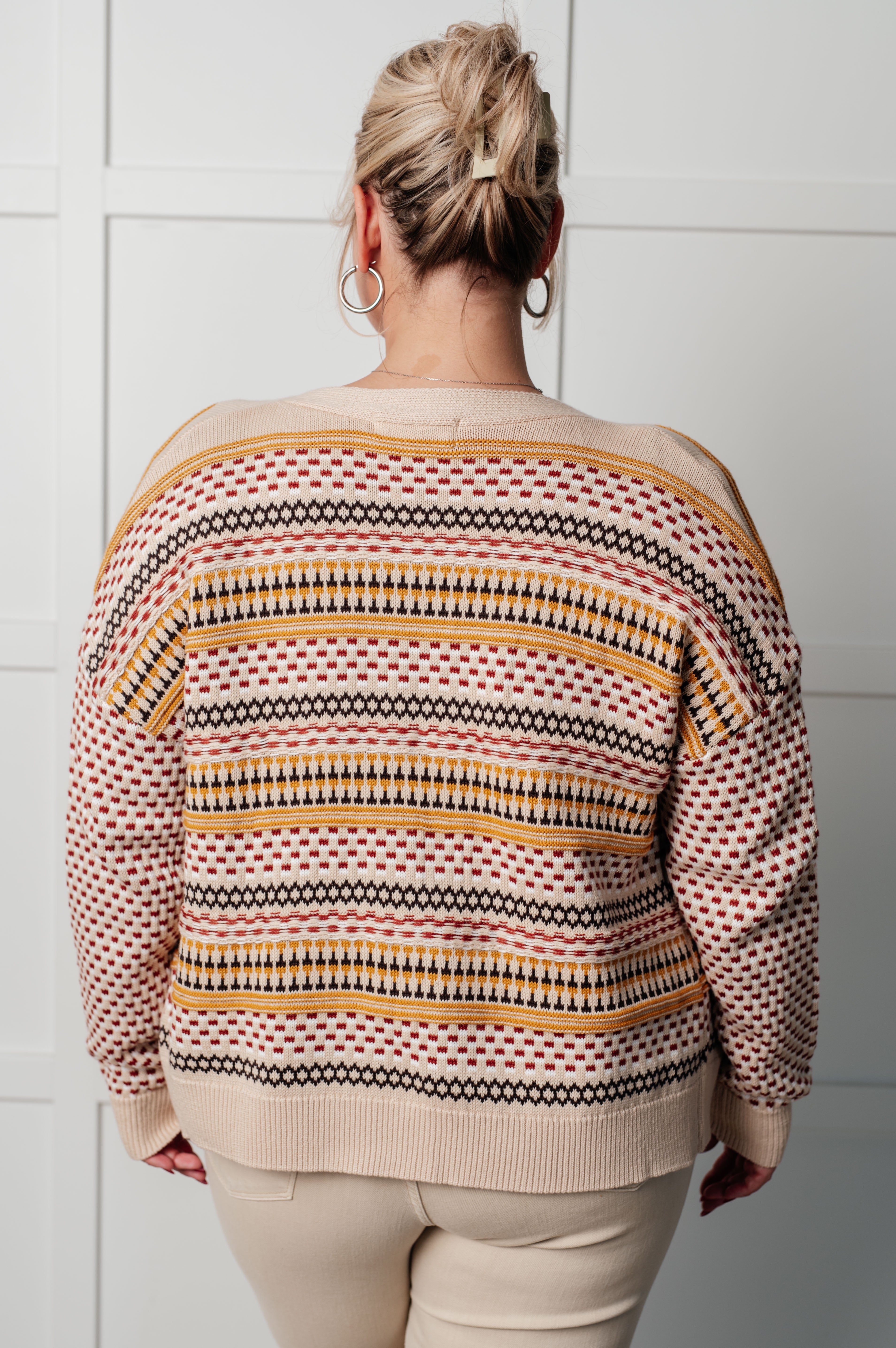 Woman seen from behind wearing a cream, mustard, and red striped Effortless Elements cardigan indoors