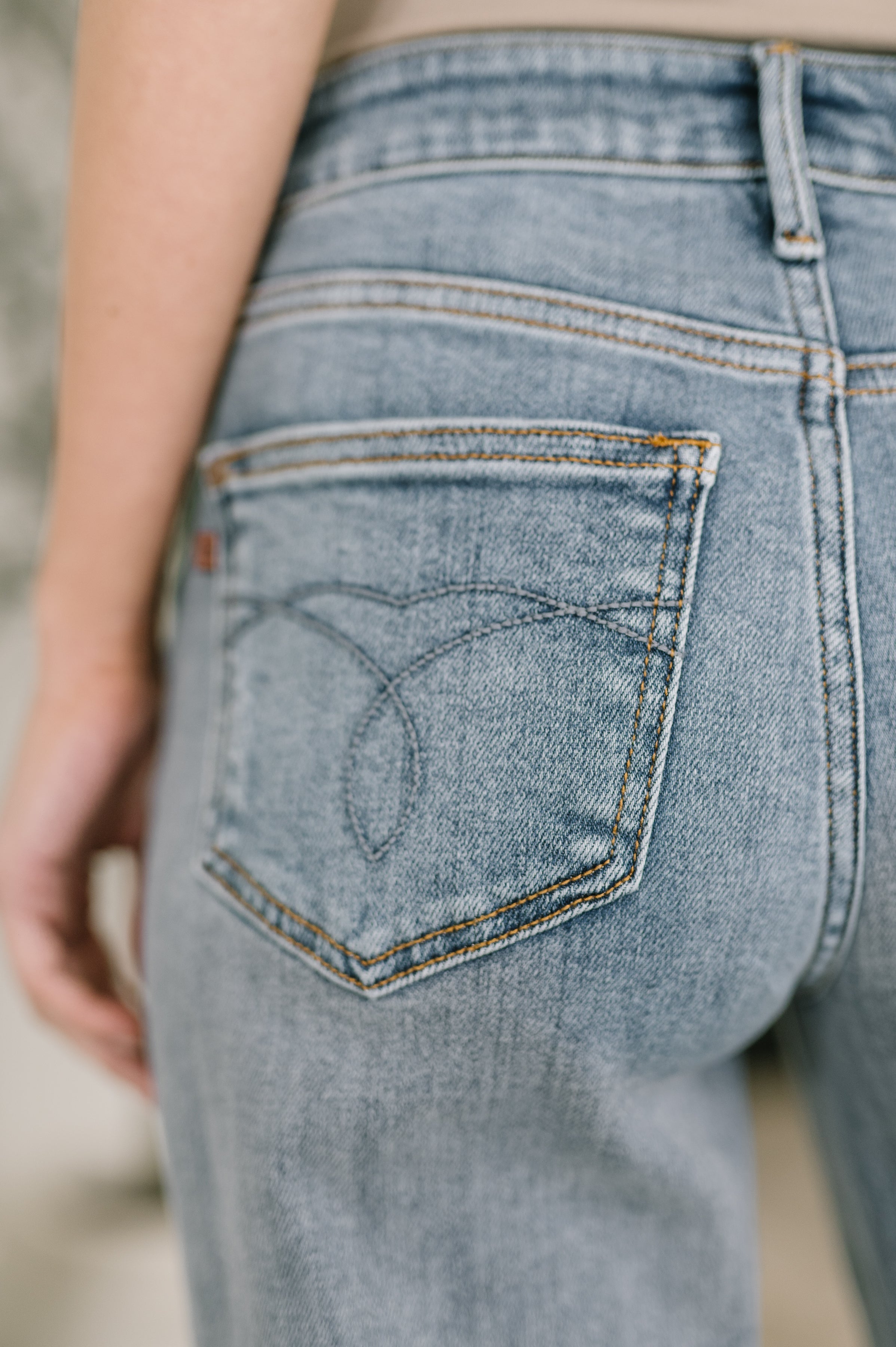 Close-up of back pocket on light blue denim jeans with subtle stitched pattern and visible seam detailing