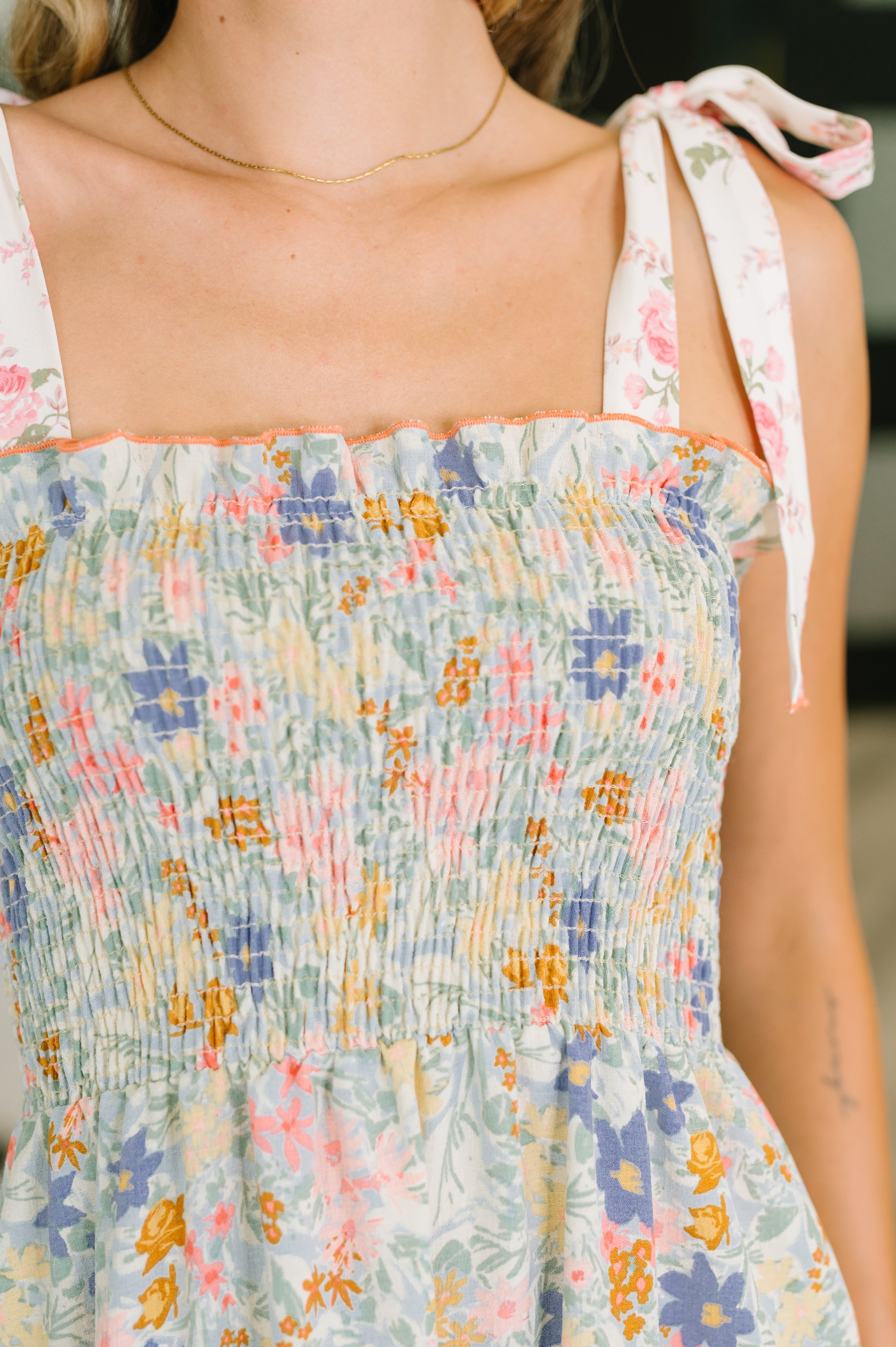 Close-up of smocked bodice with pastel floral pattern and tie shoulder straps on light summer dress