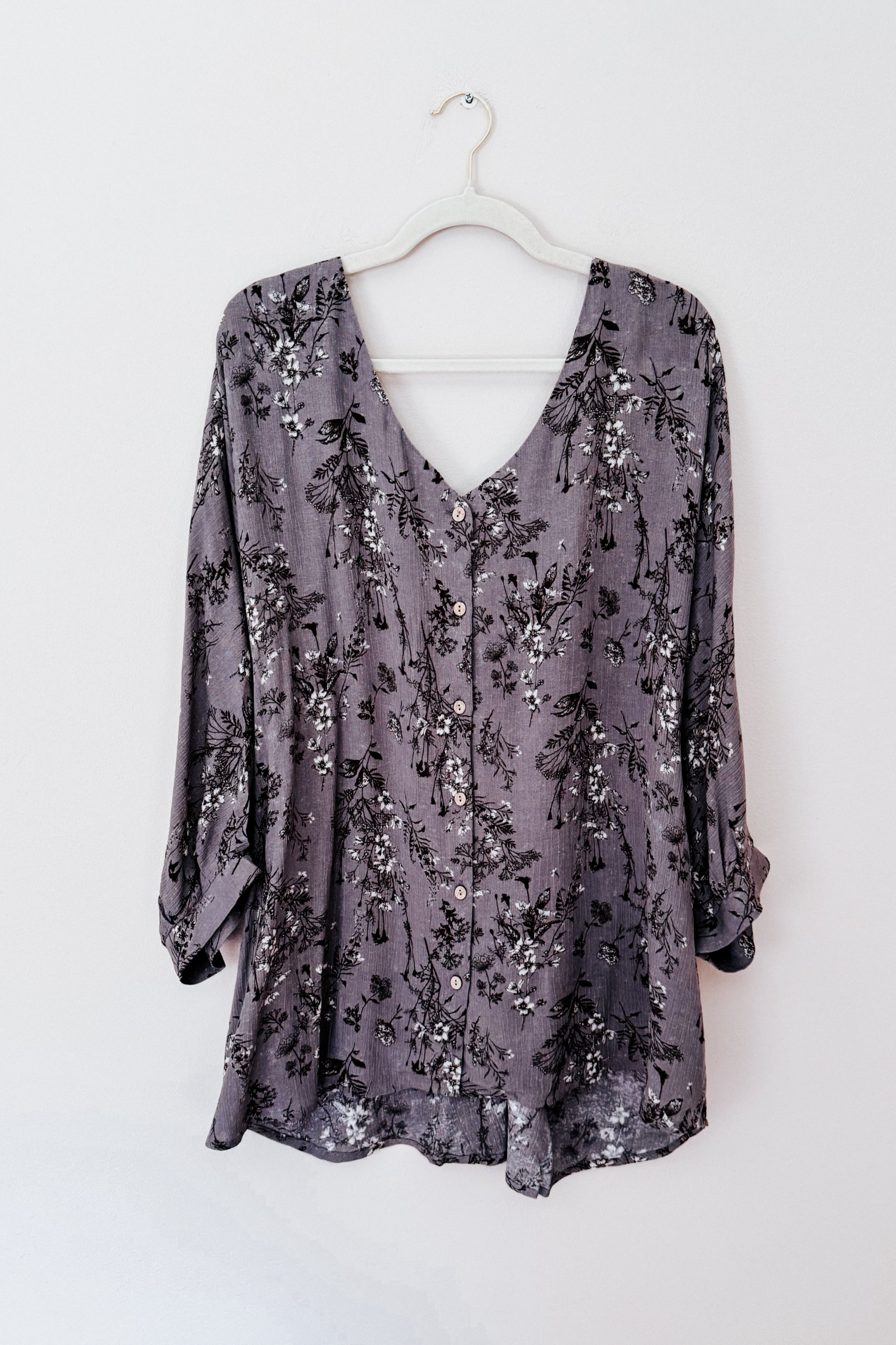 Dune grey crinkle blouse with black and white floral print and buttons hanging on white hanger against white background