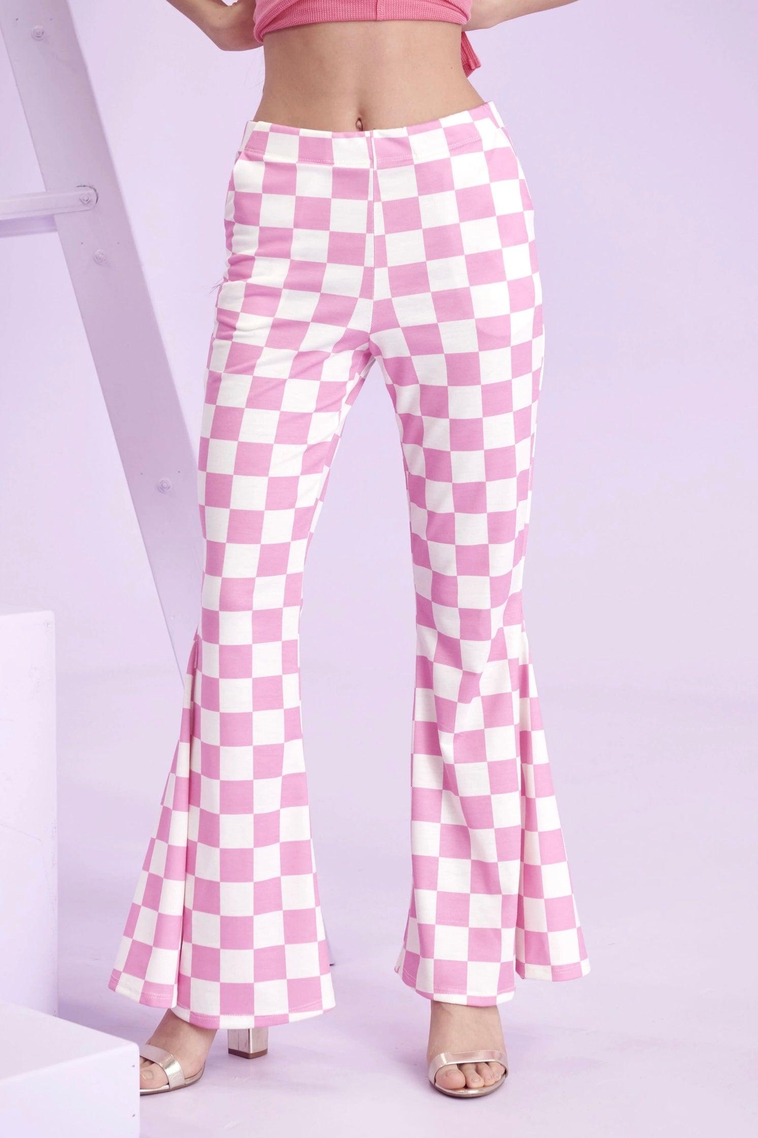 Pink and white checkerboard flared pants worn with open-toe heels against pastel purple background