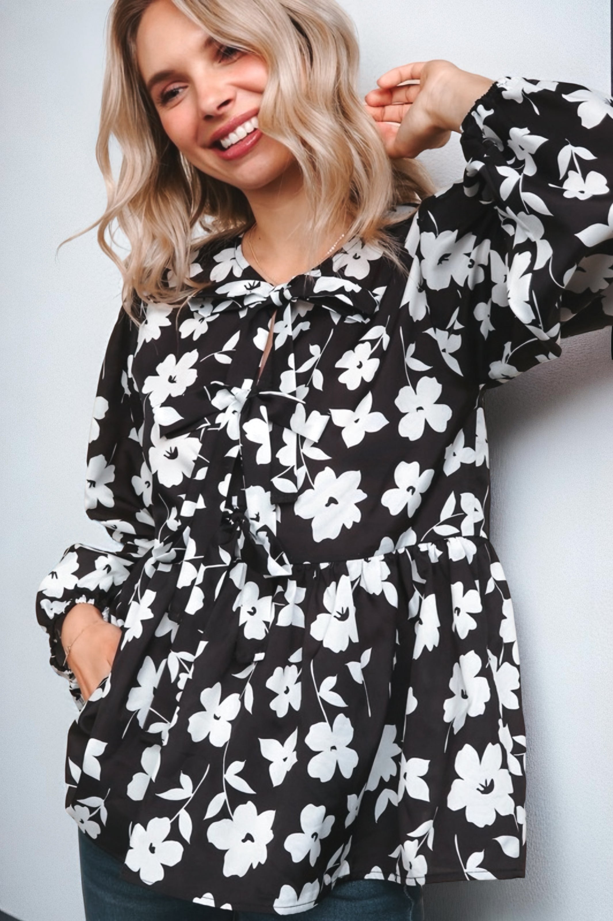 Fleur with Flair Double Bow Babydoll Top featuring a black and white floral print with long sleeves and bow details, styled casually on a smiling blonde woman.