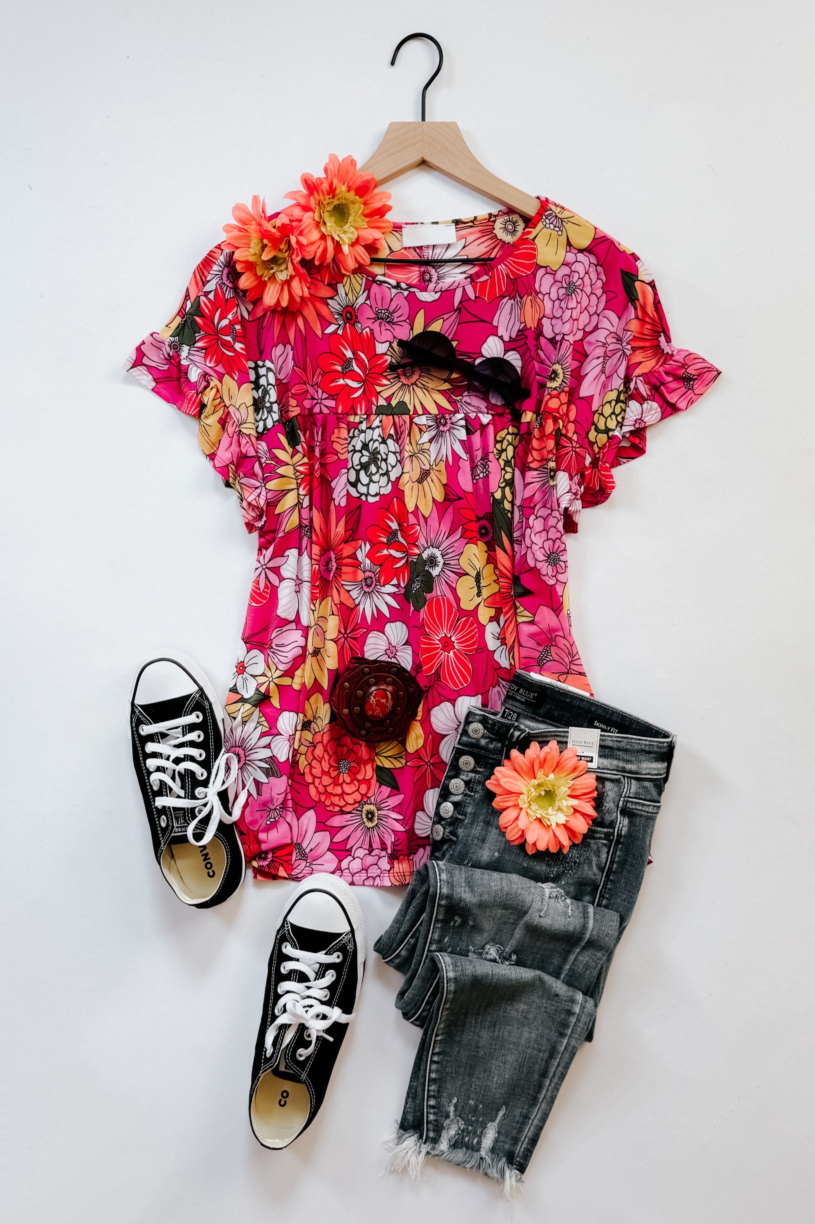 Flit About Floral Top in Pink with bold fuchsia and multicolor floral print, ruffled sleeves, styled with black sneakers and distressed jeans.