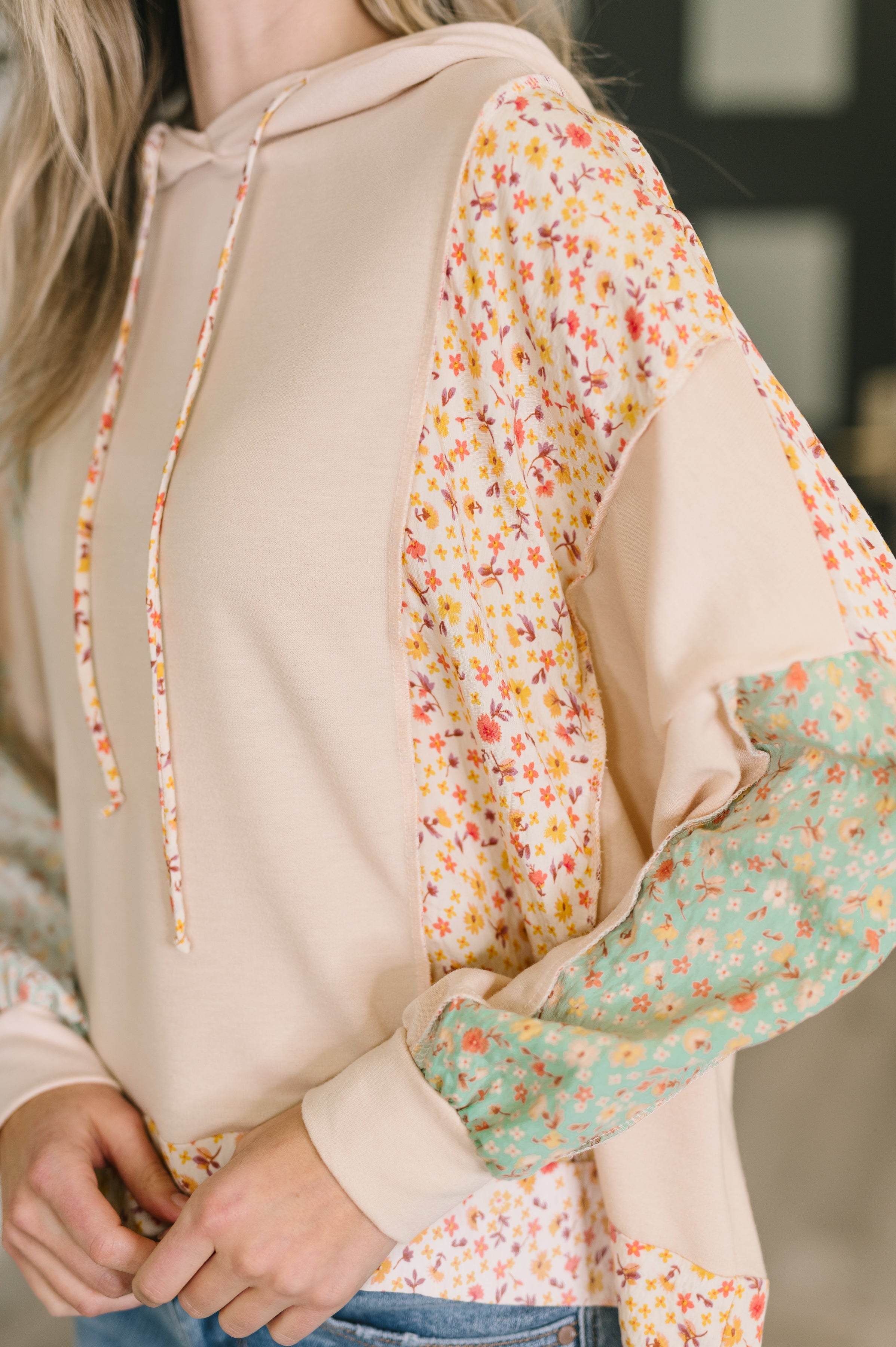 Close-up of cream Floral Patchwork Hooded Pullover featuring mixed floral patch accents on sleeve and side panels