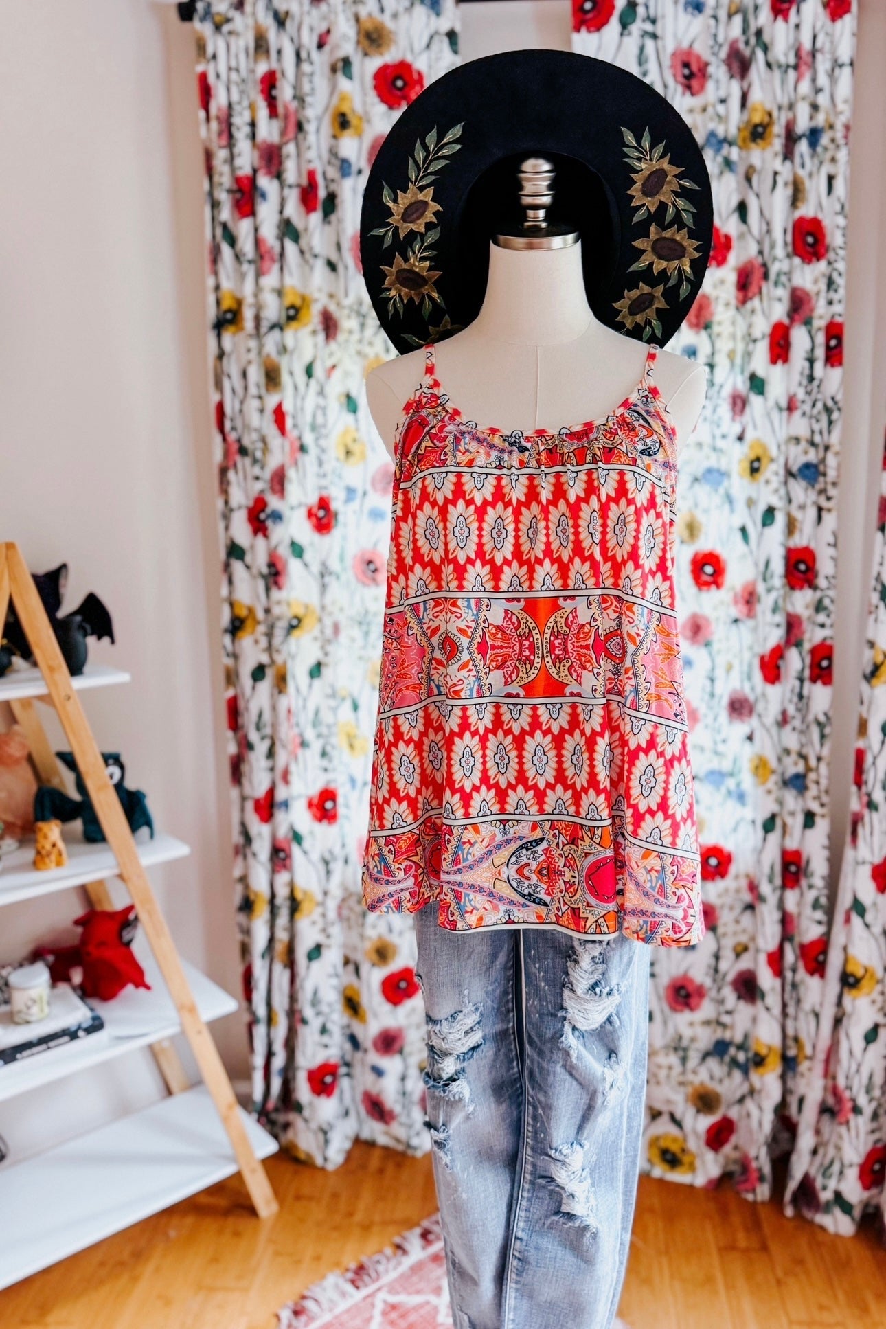 Mannequin wearing red mixed print sleeveless tank with a-line silhouette paired with distressed light-wash jeans indoors