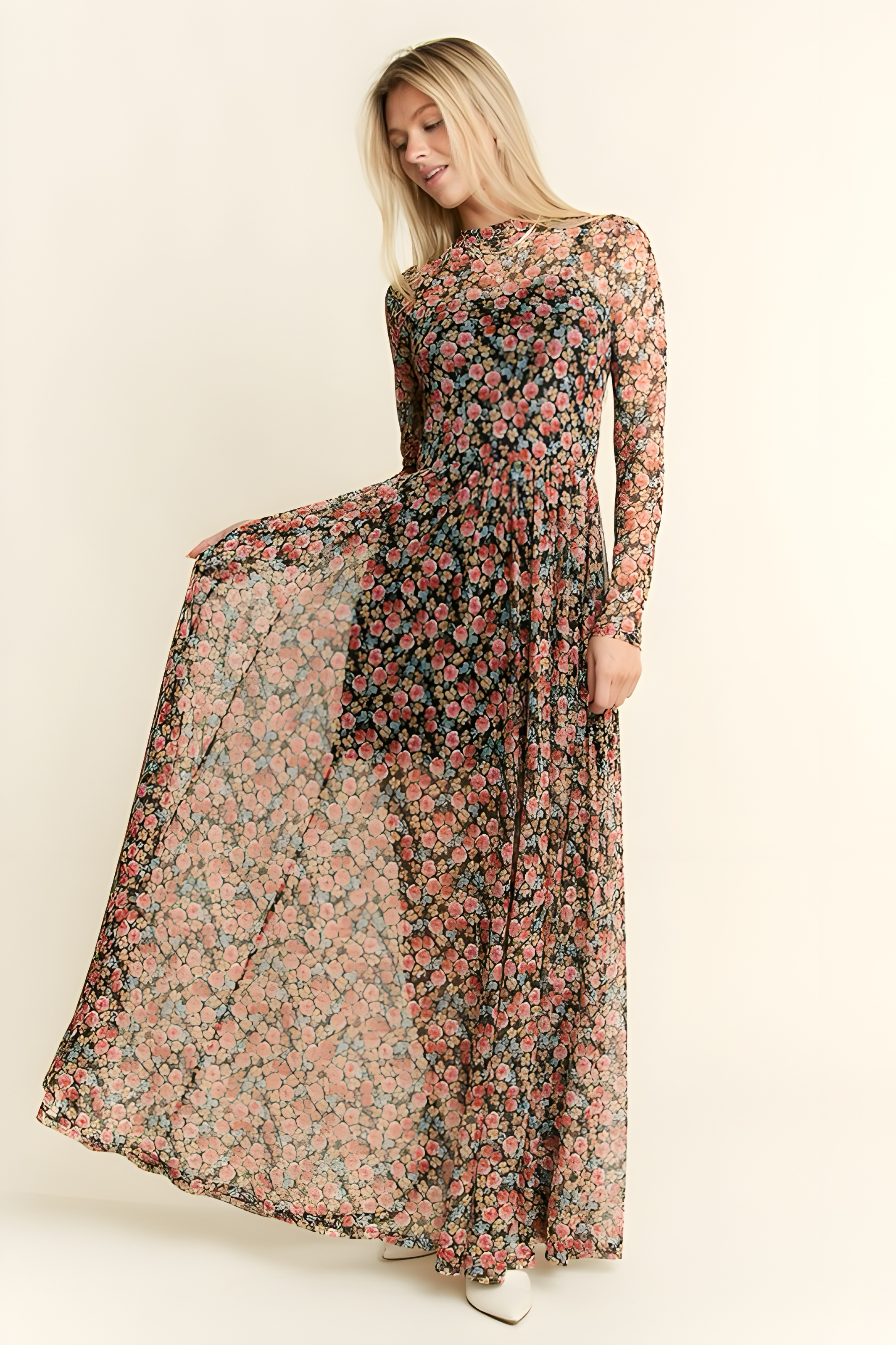 Woman wearing flowing long sleeve mesh maxi dress with delicate red and pink floral print on black background