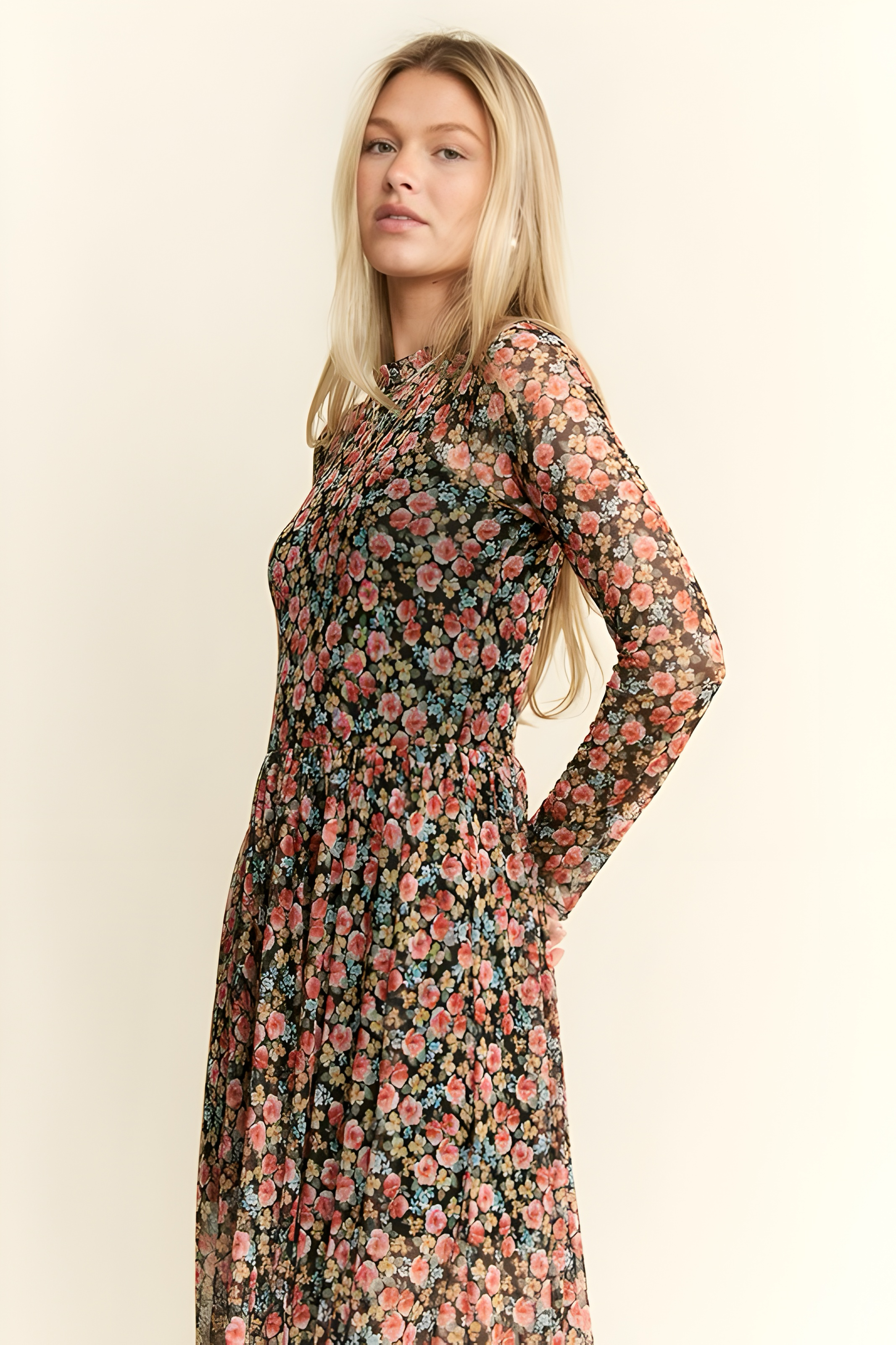 Blonde woman wearing sleeved floral print mesh maxi dress with pink and blue flowers on black fabric