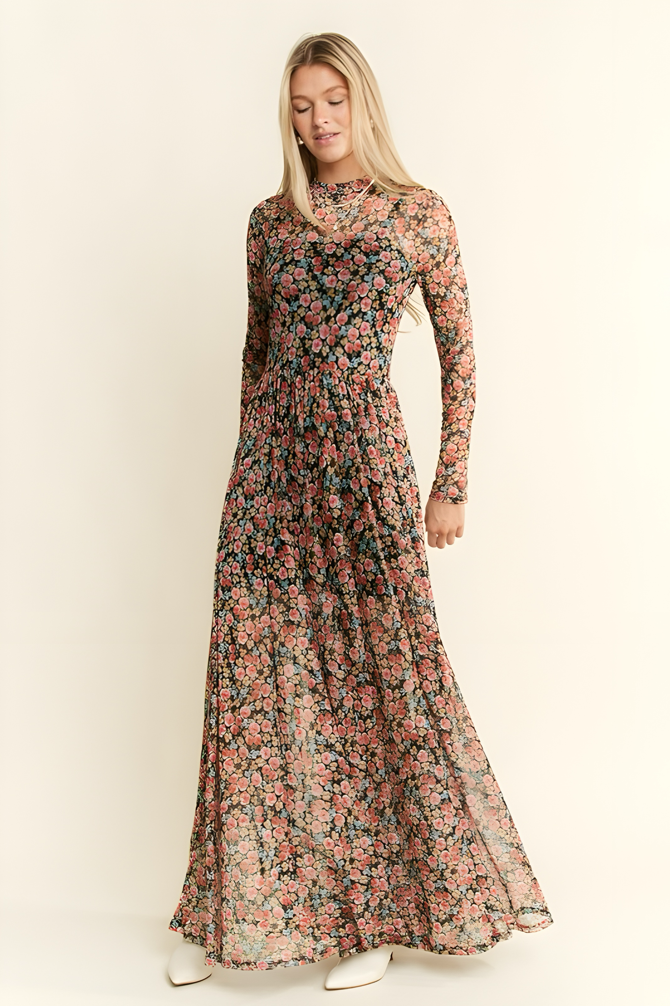 Woman standing wearing long sleeve floral print mesh maxi dress with pink and orange blooms on dark background