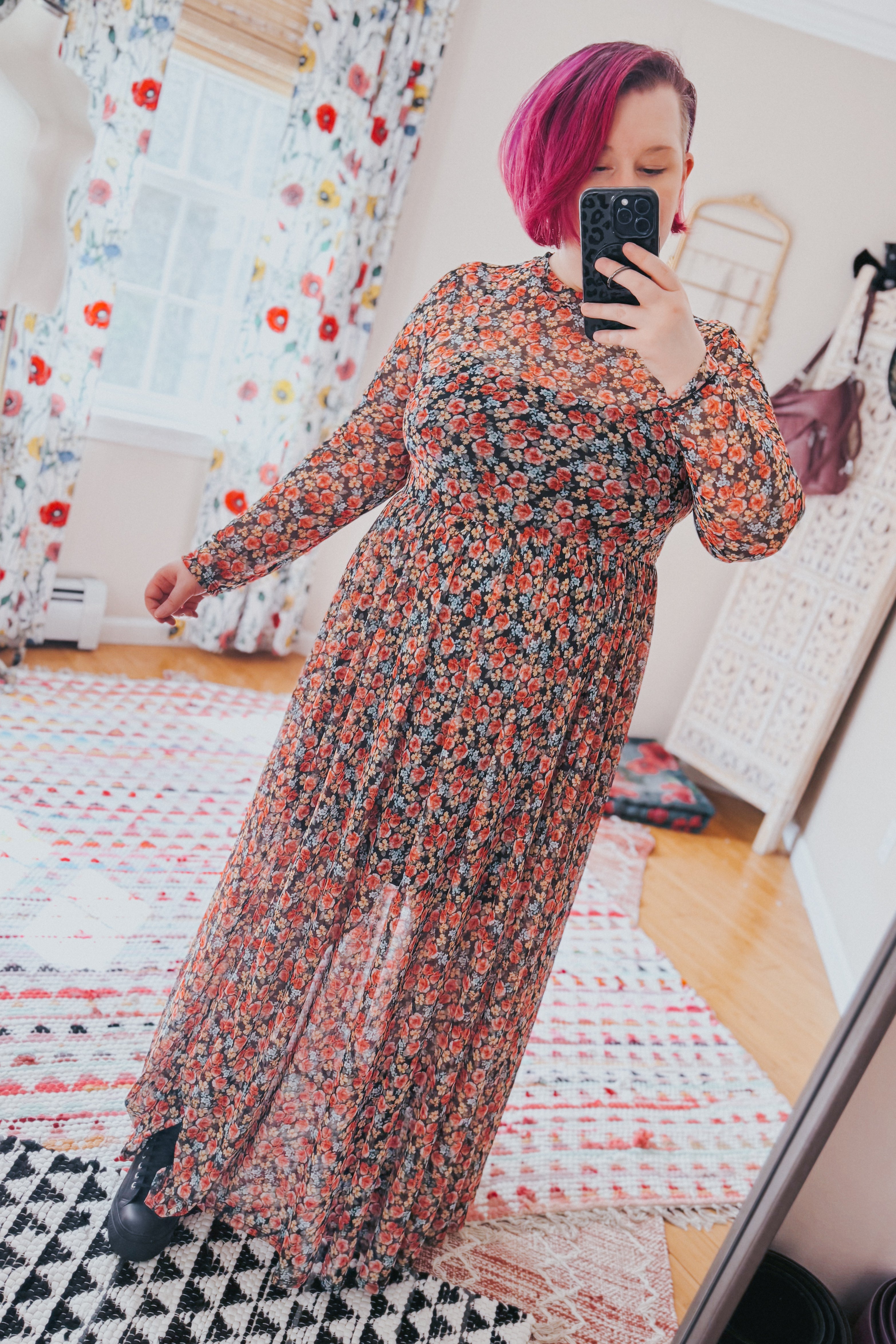 Woman taking selfie wearing long sleeve red floral mesh maxi dress with fitted waist in bright room with patterned rugs