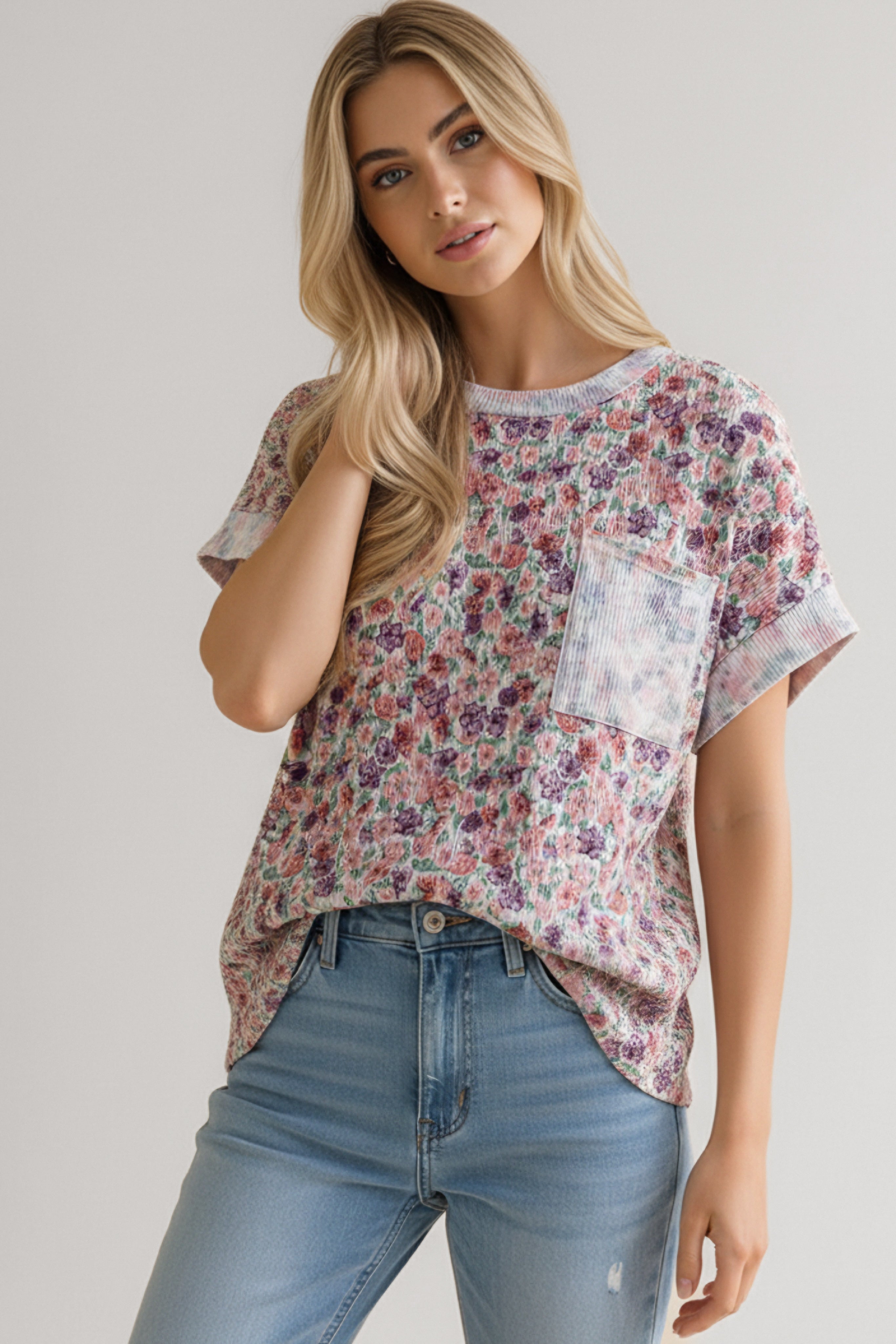 Woman wearing purple floral pocket tee with rolled sleeves paired with light blue high-rise jeans indoors