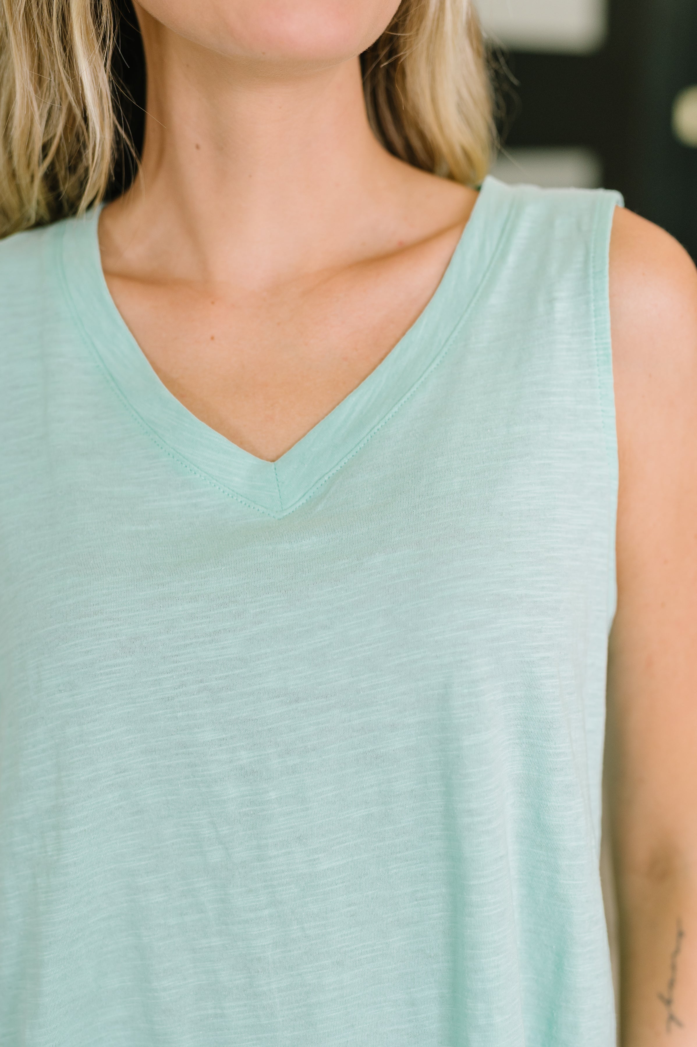Close-up of sleeveless mint V-neck tank with soft heathered fabric in a relaxed, versatile style