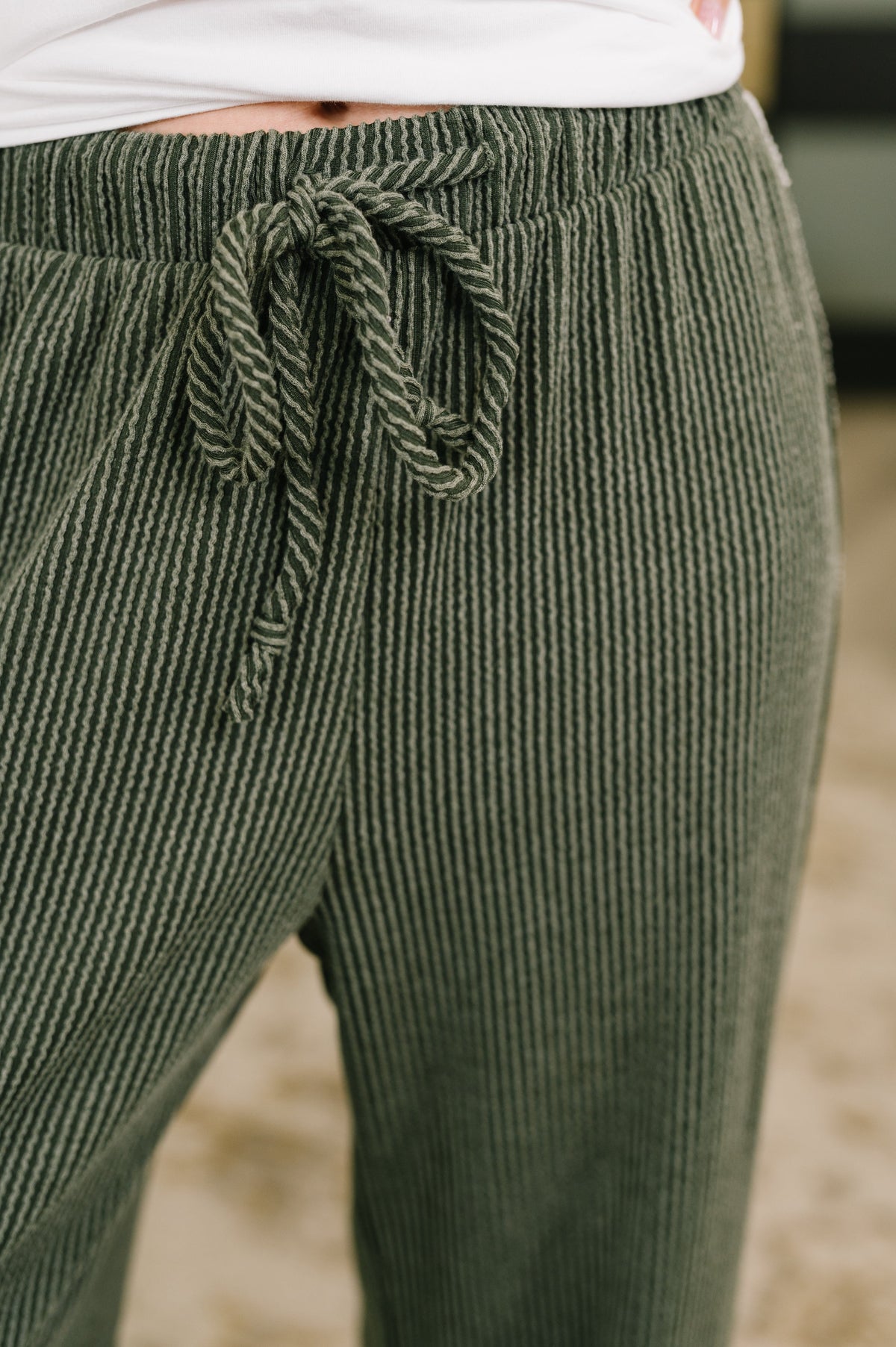 Close-up of olive high waisted knit bottoms with cable ribbed texture and a comfortable adjustable drawstring waist