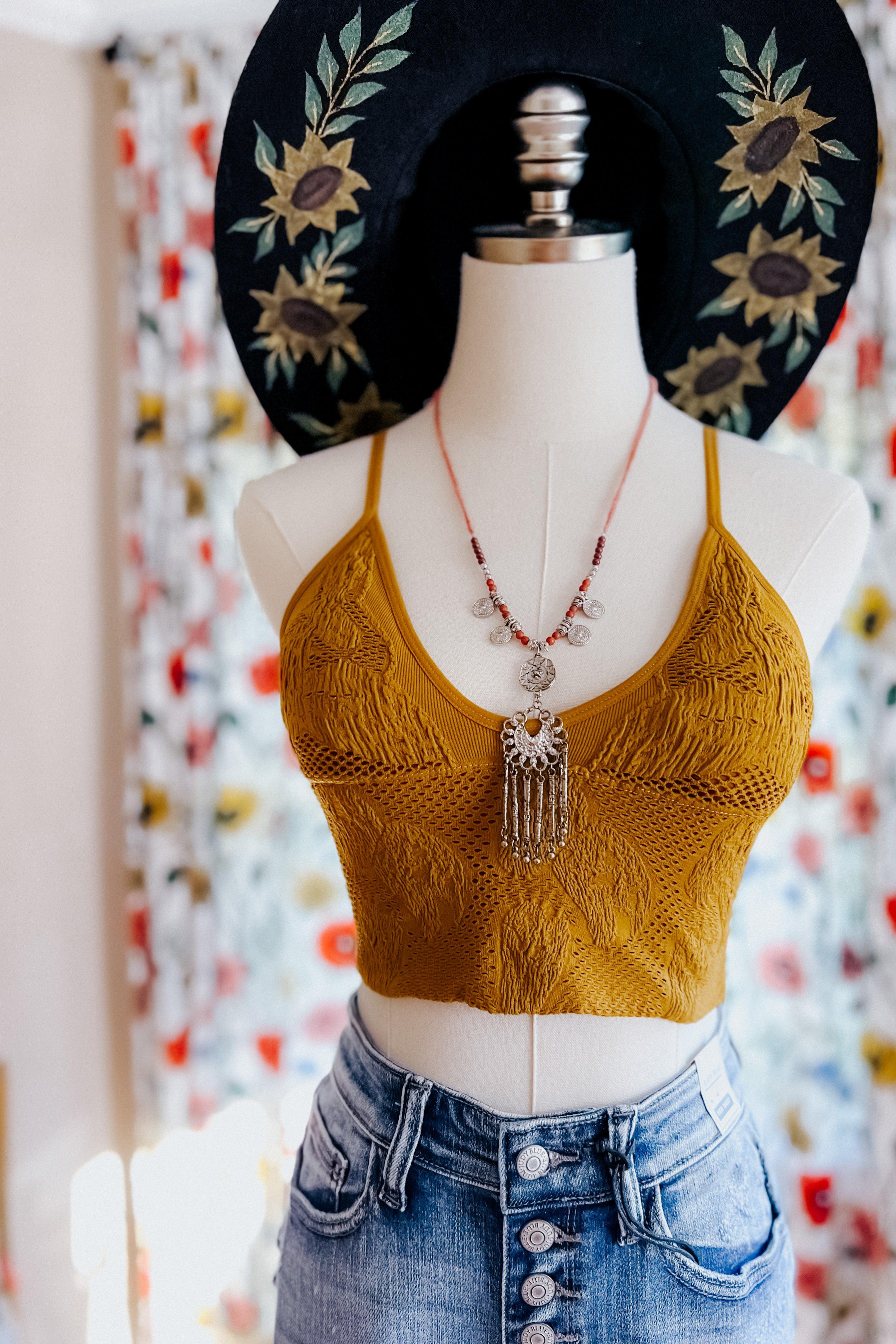 Mustard textured seamless padded brami with floral knit pattern styled on mannequin wearing boho necklace and denim skirt