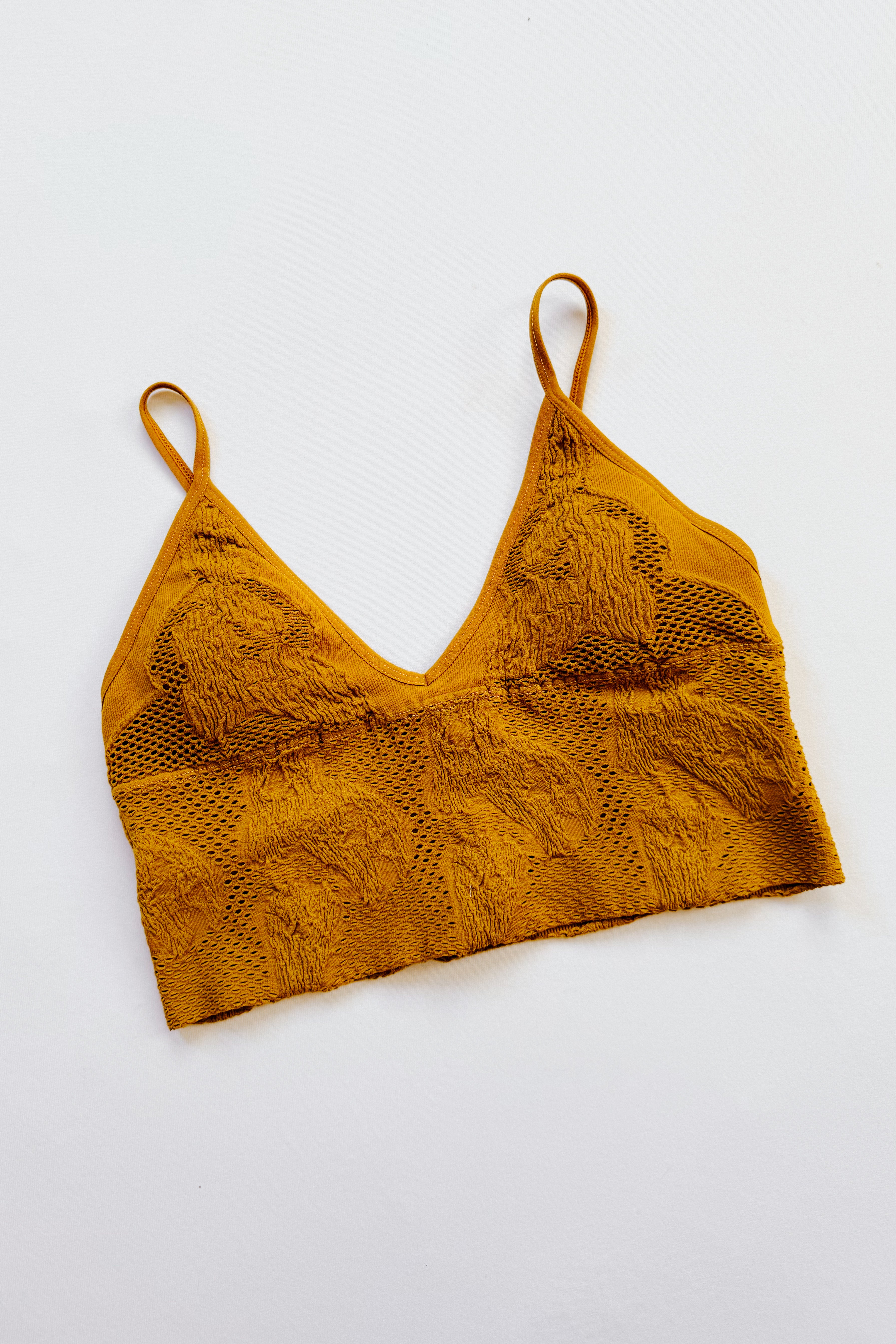 Mustard textured seamless brami with thin adjustable straps laid flat on white background