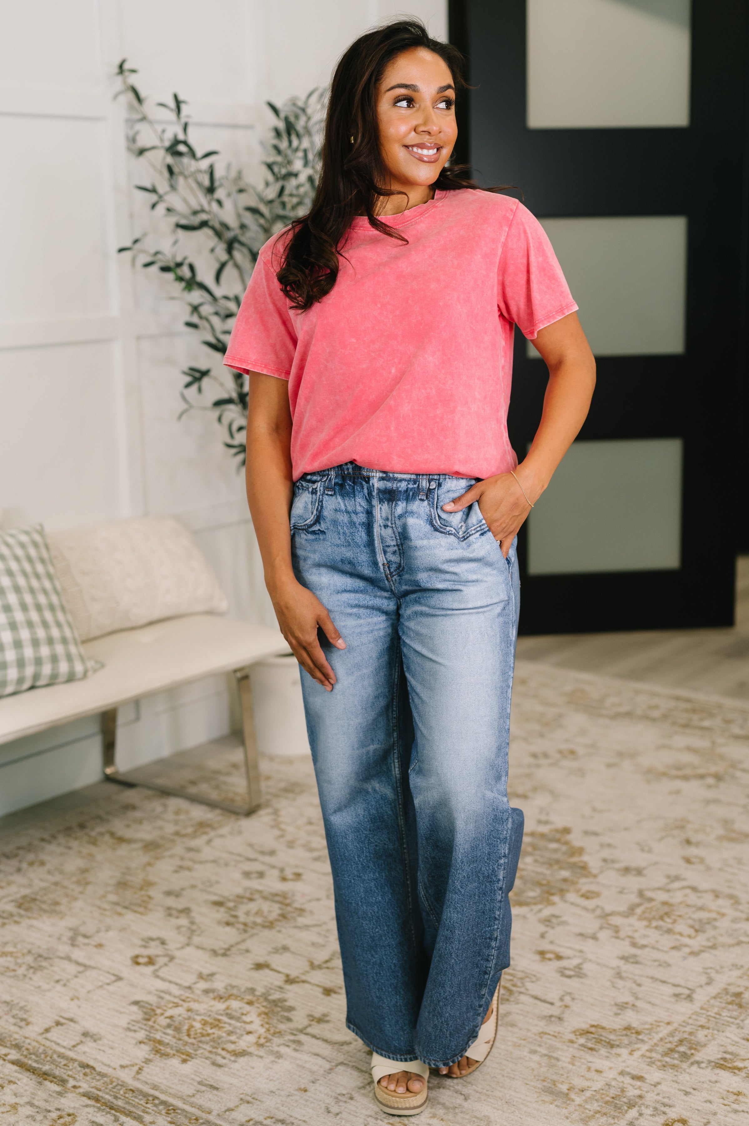Woman wearing a plush mineral wash fuchsia tee with relaxed fit paired with light blue wide-leg jeans indoors