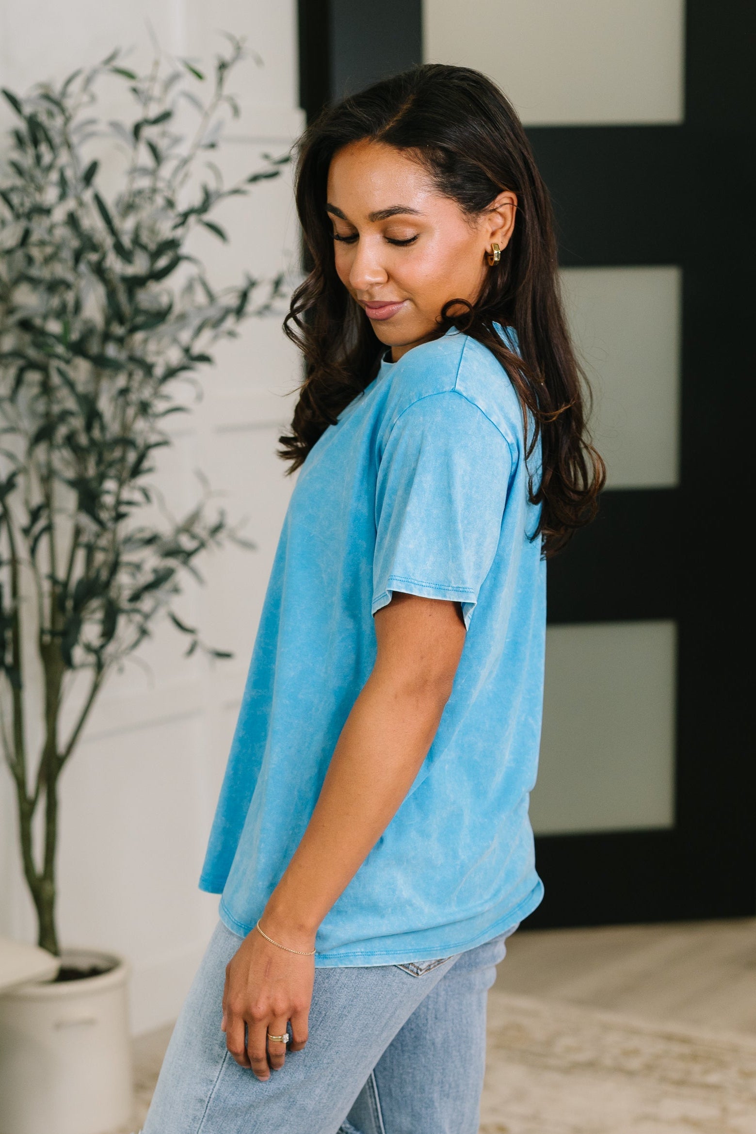 Side view of woman wearing soft deep sky blue mineral wash tee paired with light wash jeans indoors
