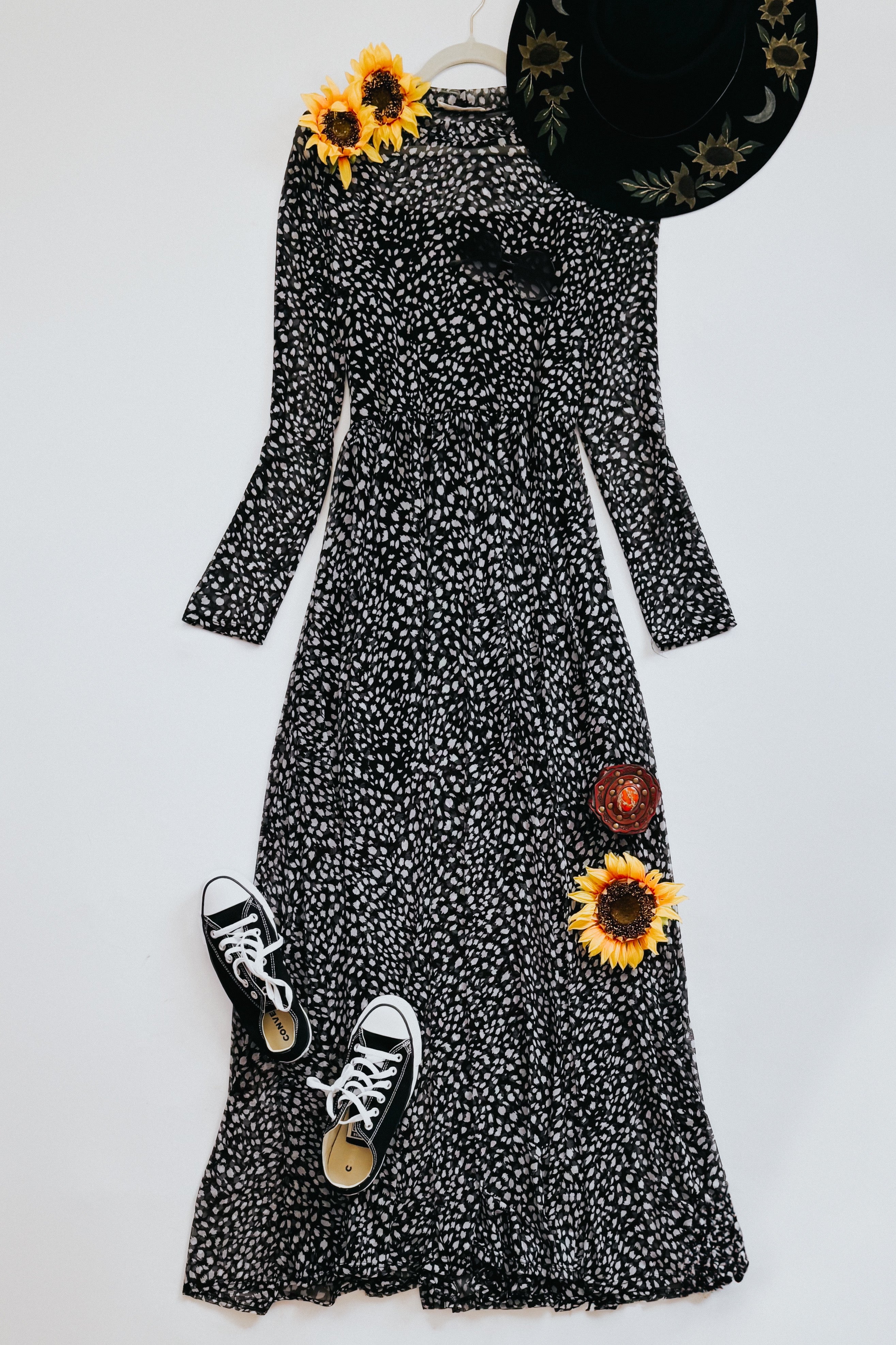 Black Hendrix long sleeve mesh maxi dress with animal print, styled with black hat, sneakers, and sunflowers on white background