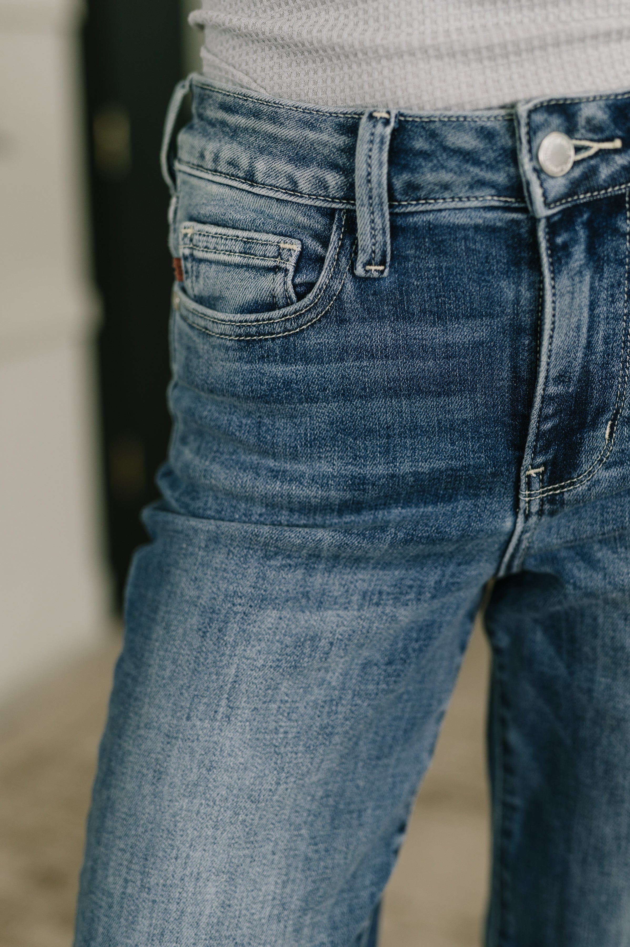 Close-up of mid rise blue straight jeans with subtle fading and textured white top edge visible