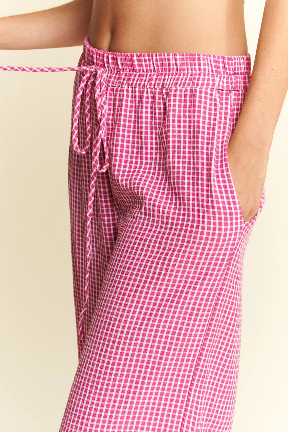 Close-up of pink In The Groove Checkered Print Pants featuring elastic waistband and drawstring with hand in pocket