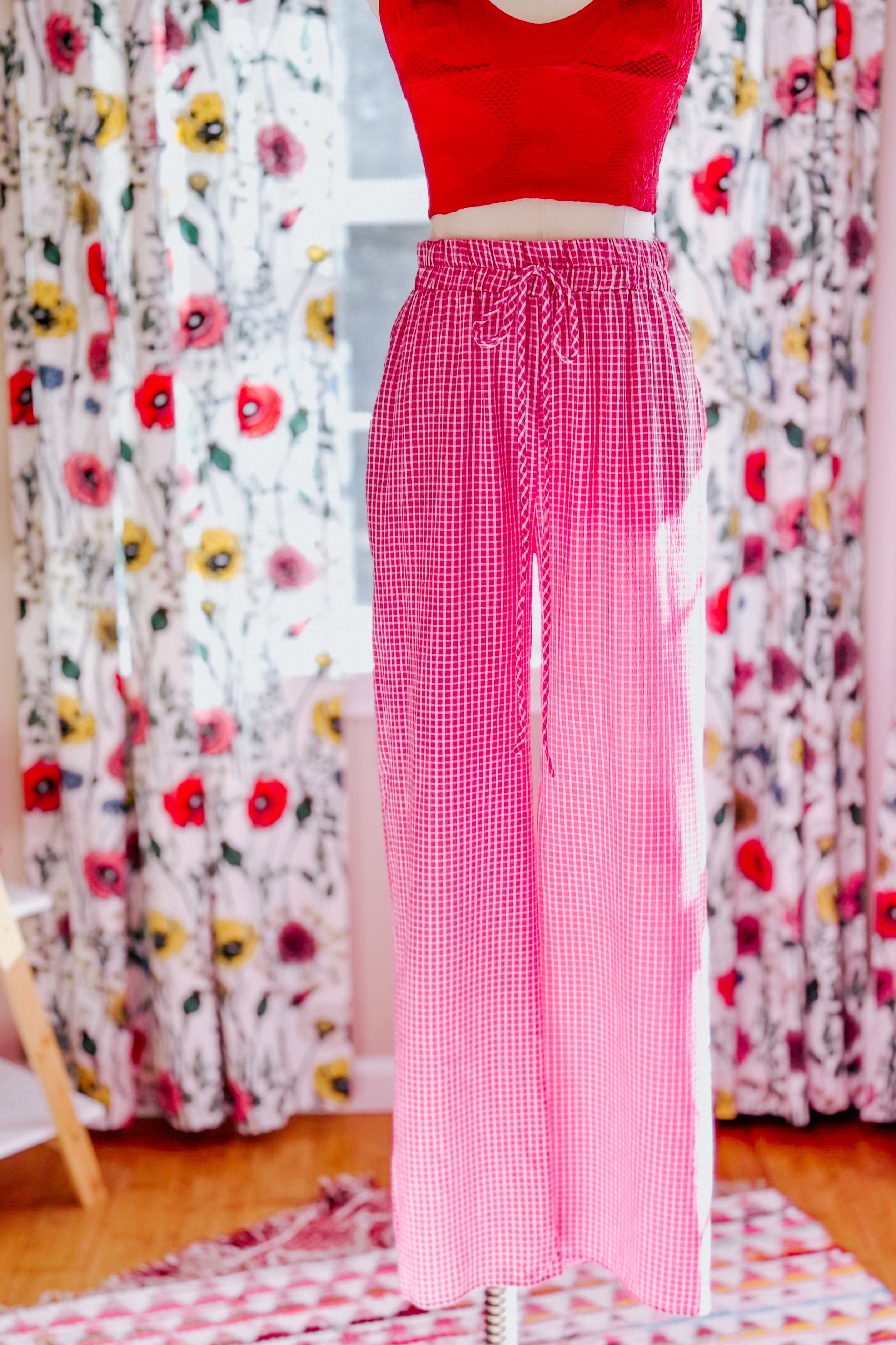 Pink In The Groove Checkered Print Pants with drawstring waist displayed in bright room with floral curtains