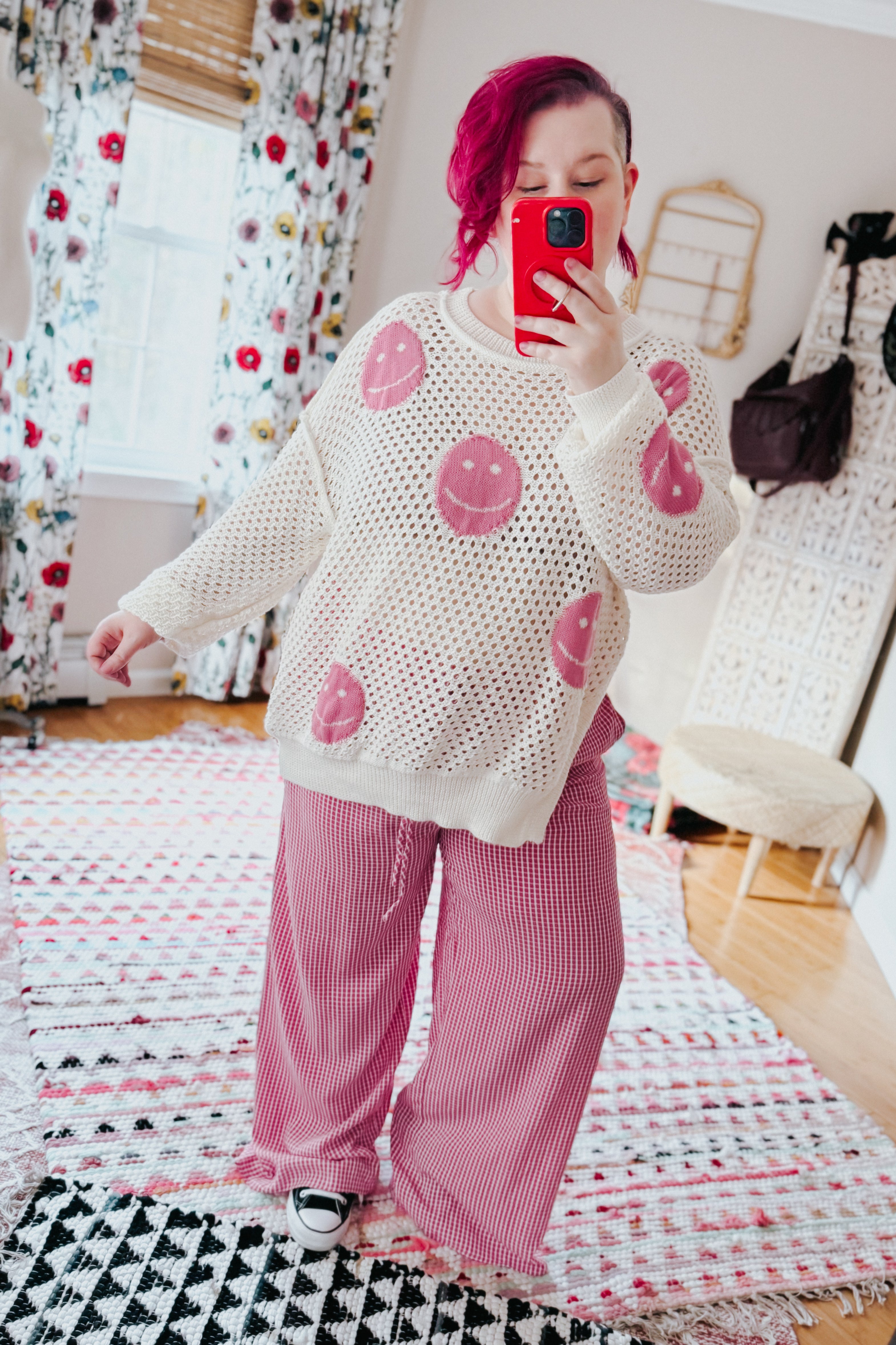 Woman wearing pink In The Groove Checkered Print Pants with wide legs paired with white knit sweater taking selfie indoors