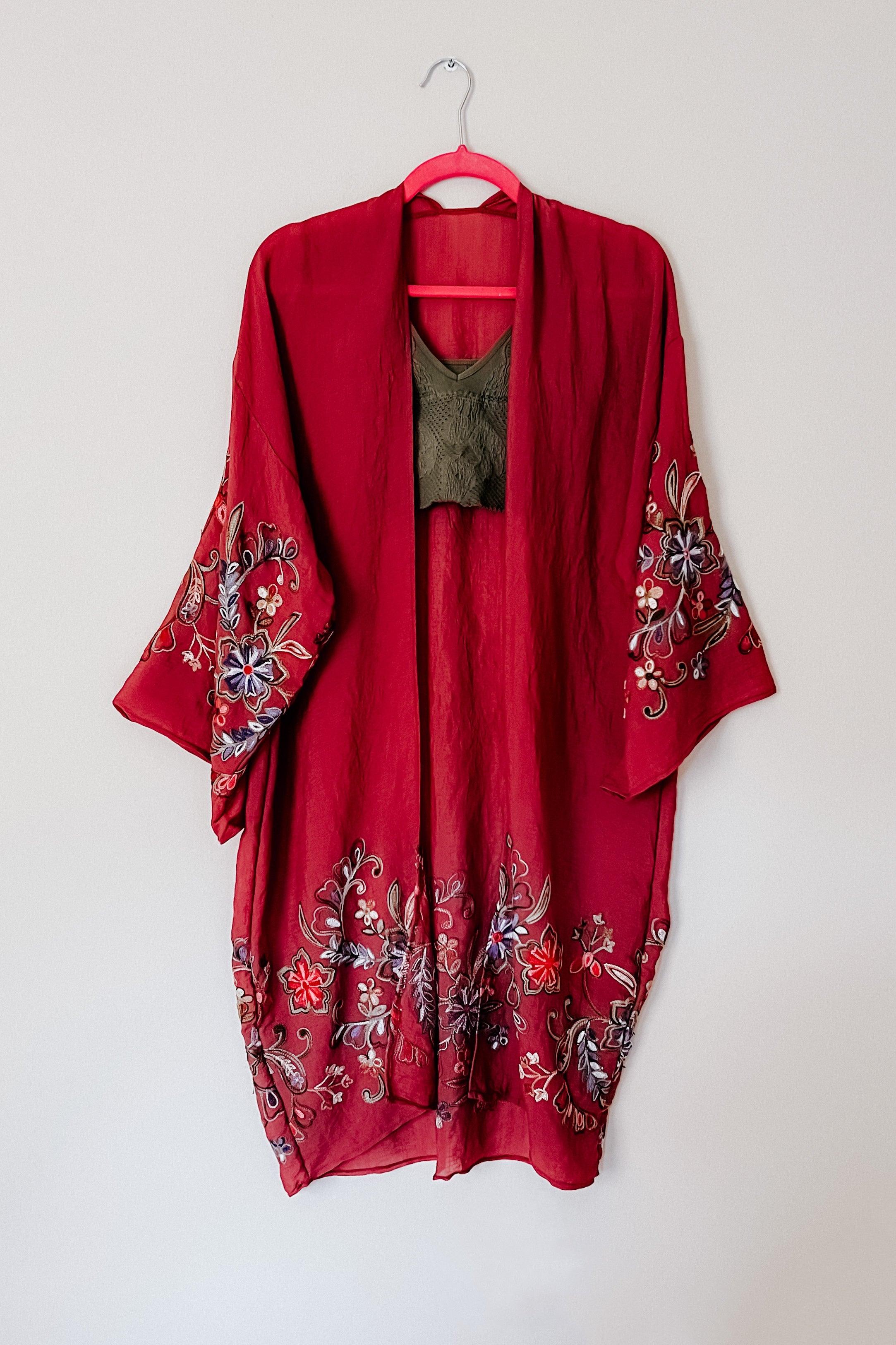 Crimson In The Meadow embroidered duster with detailed floral embroidery on sleeves and hem hanging on pink hanger