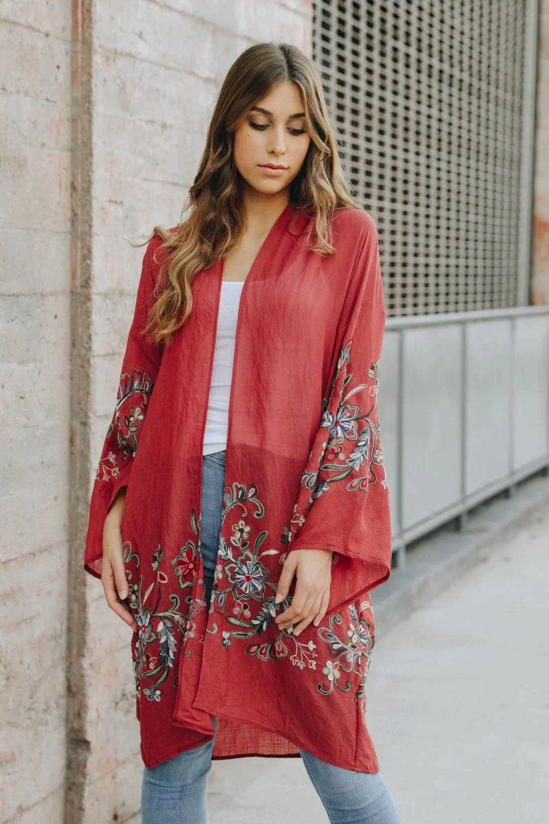 Woman wearing crimson In The Meadow embroidered duster with floral embroidery and relaxed fit standing outdoors