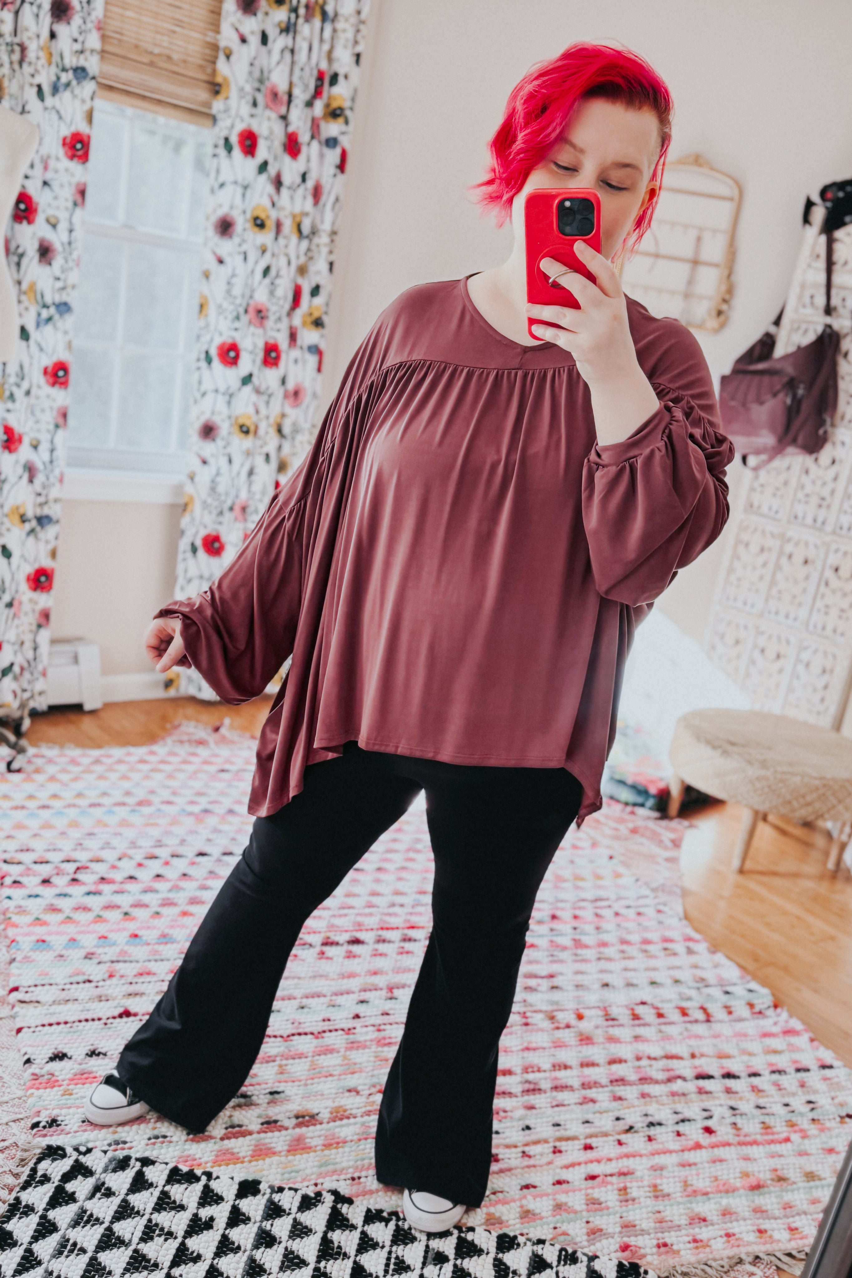 Plus-size woman taking mirror selfie wearing wine In This Groove modal knit top with gathered sleeves and black pants indoors