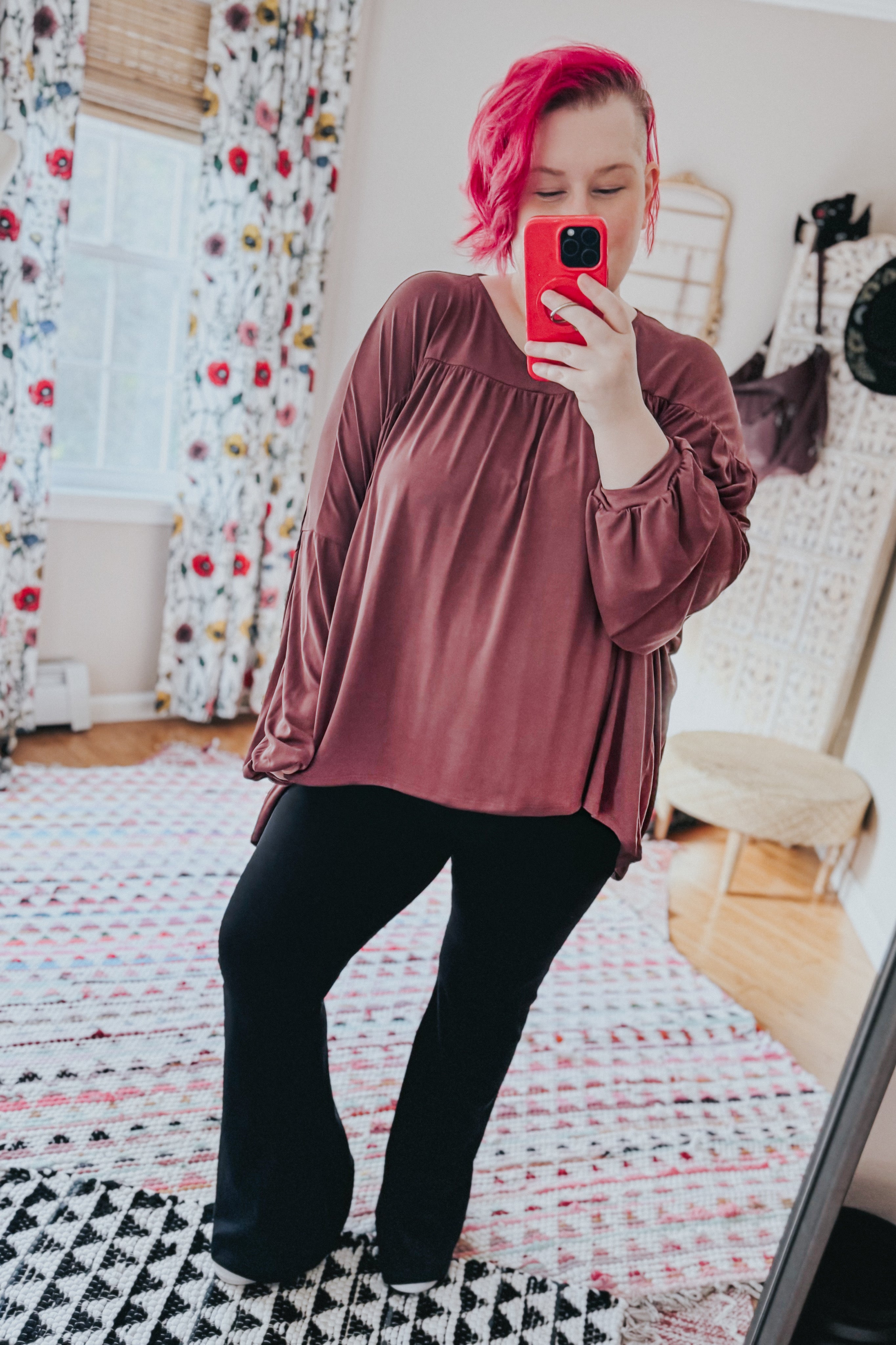 Woman taking mirror selfie wearing wine In This Groove modal knit top with gathered yoke and black pants in bright room