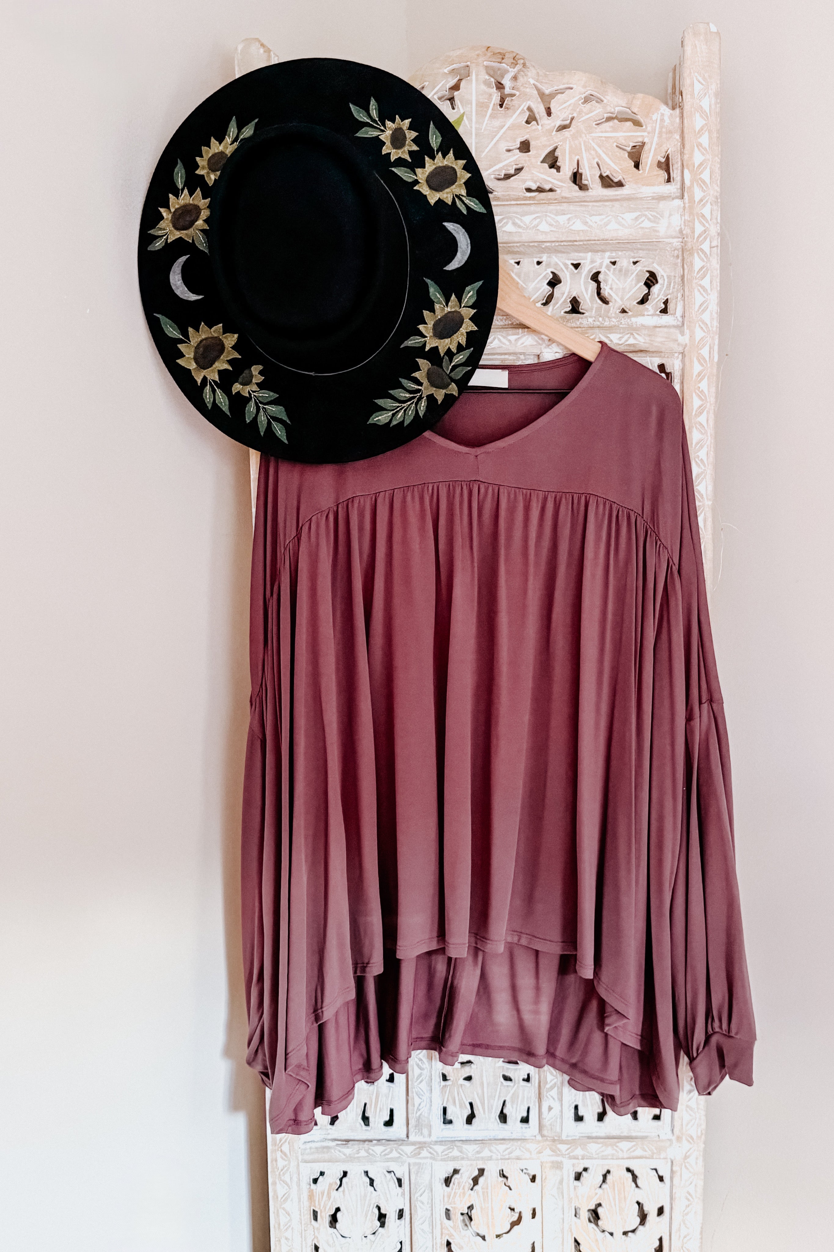 Wine In This Groove modal knit top with gathered yoke and long pleated sleeves hanging on carved wooden screen