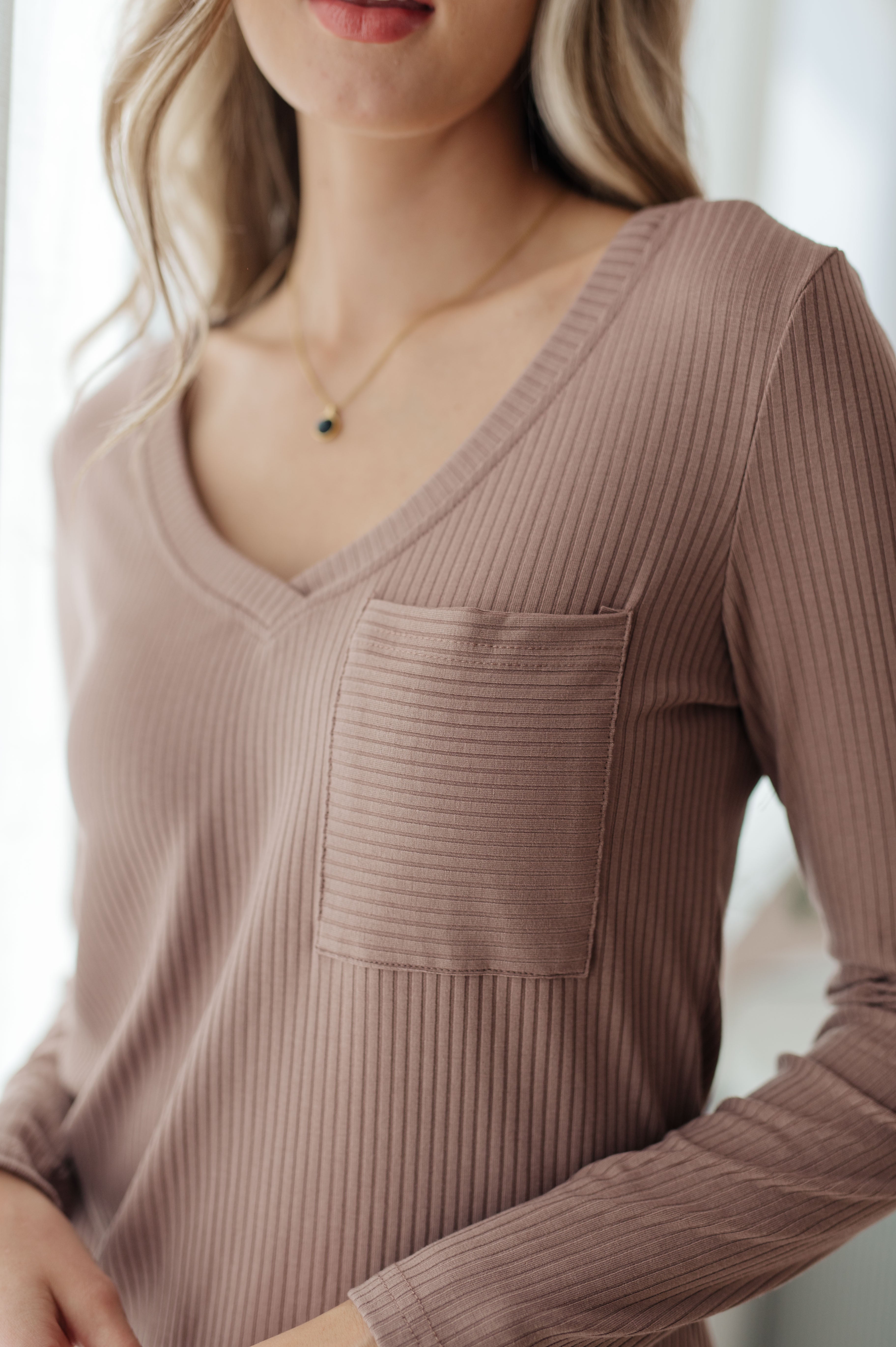 Close-up of woman wearing taupe Indeed You Do long sleeve V-neck top with ribbed fabric and chest pocket indoors