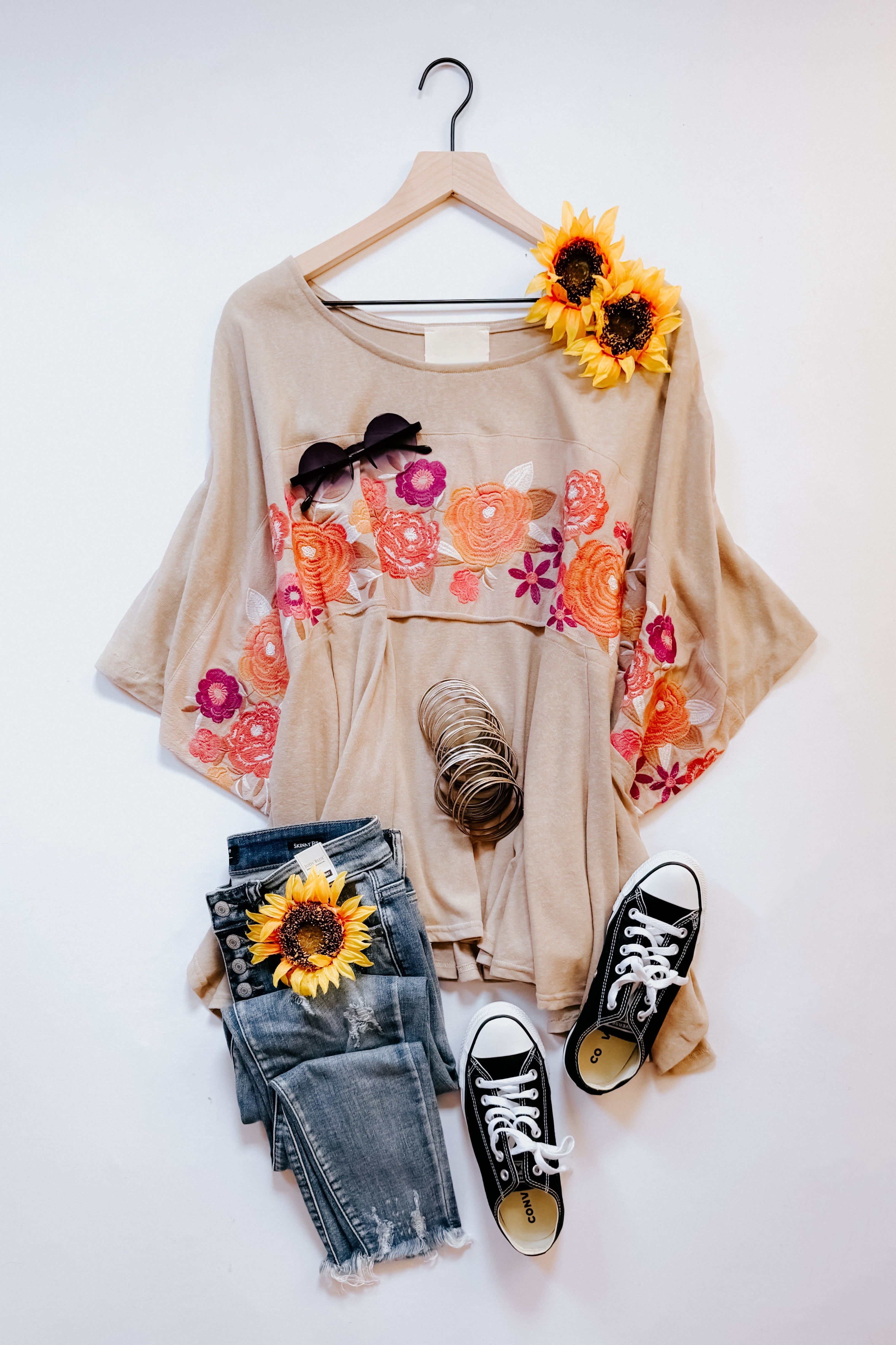 Mocha Isabel embroidered tunic with floral pattern styled with distressed blue jeans, black sneakers, and sunflower accessories