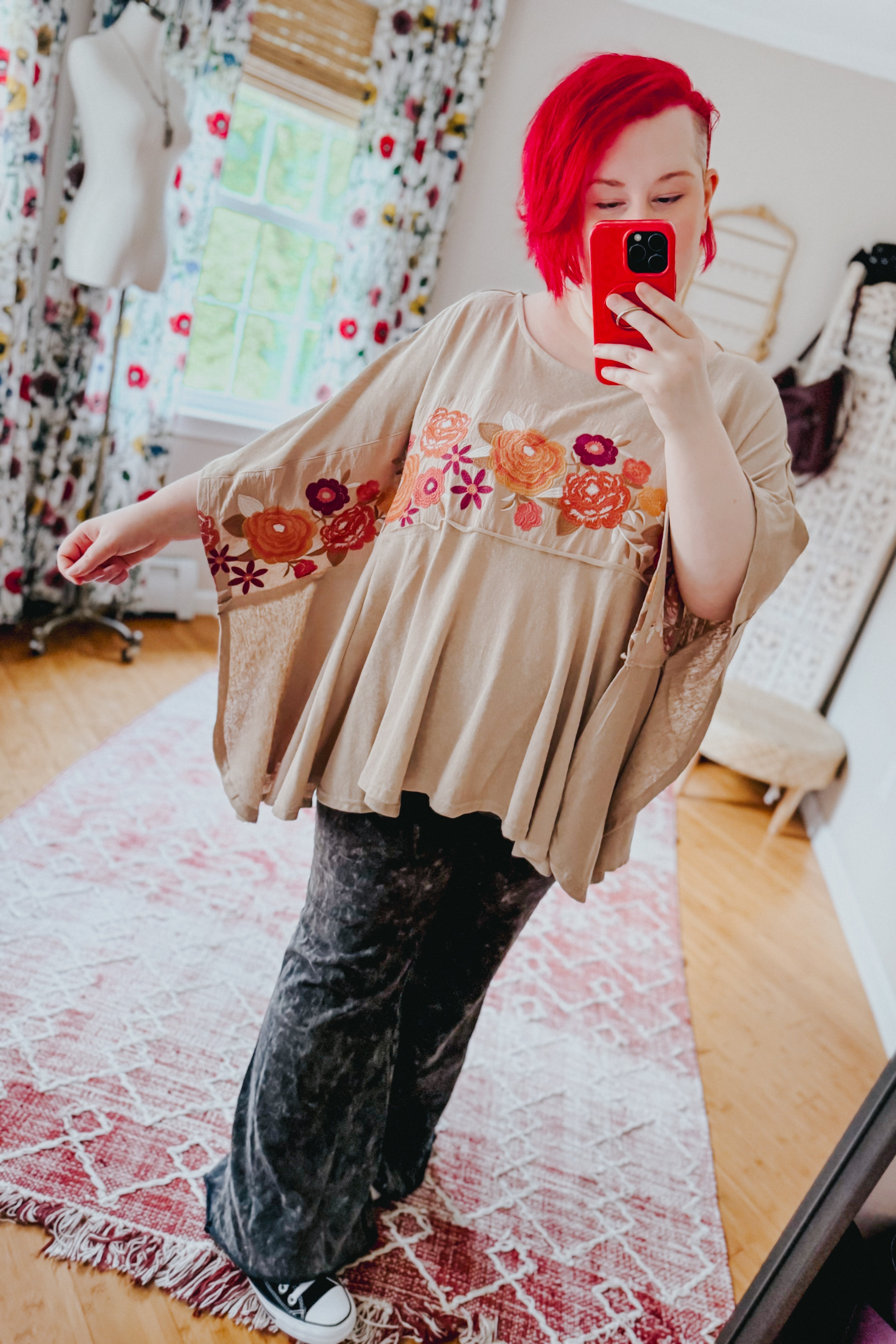 Woman taking mirror selfie wearing mocha Isabel tunic with colorful floral embroidery and flowy, wide sleeve design